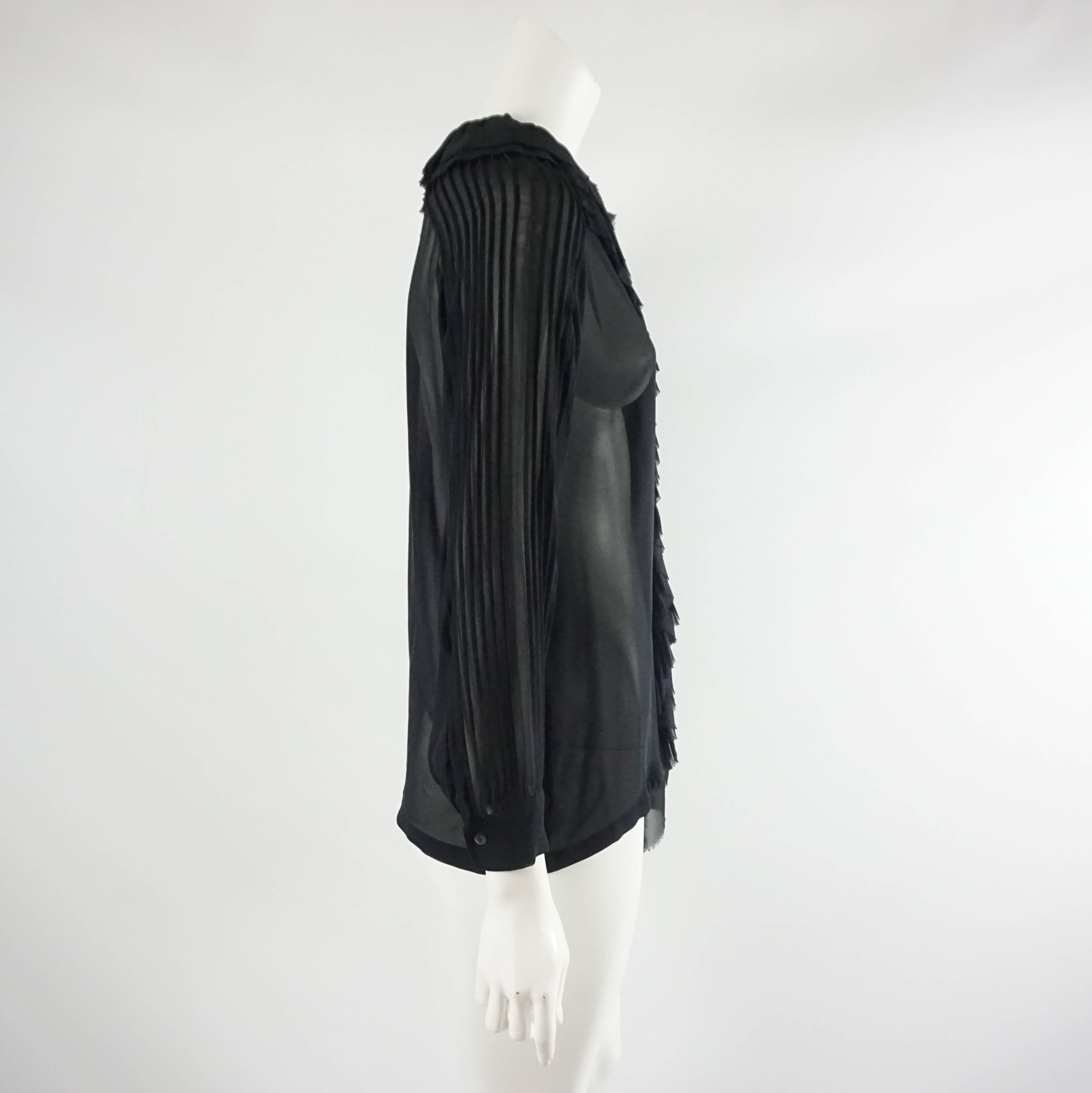 This Dries Van Noten blouse is black and is made of silk chiffon. The top has pleats along the sleeves and ruffles along the neck and the front. It is in excellent condition with minimal wear and no visible wear on fabric. Size 36, circa 21st