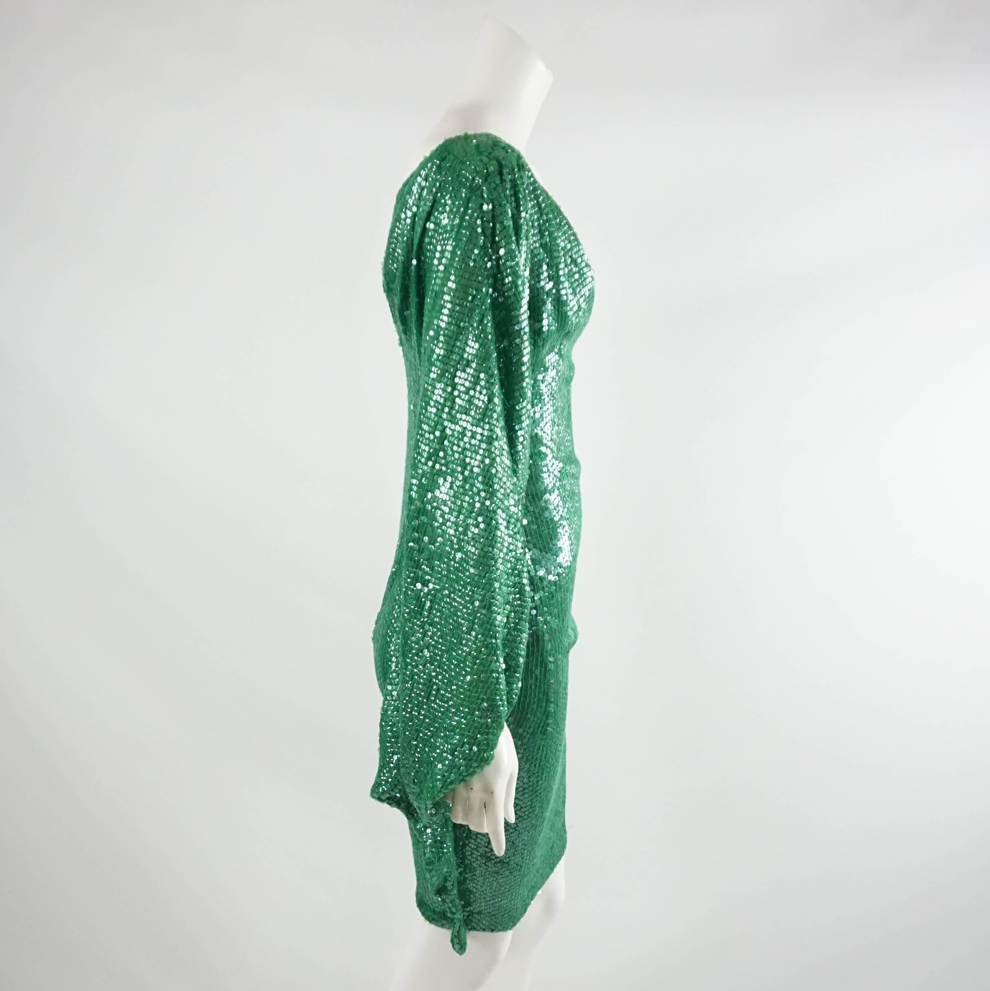 This Naeem Khan green sequin dress is a show stopper. It features a fitted bodice and a loose, cascading single sleeve. The piece is in fair condition with wear consisting of small areas with loose or missing sequins near the shoulder, sides,