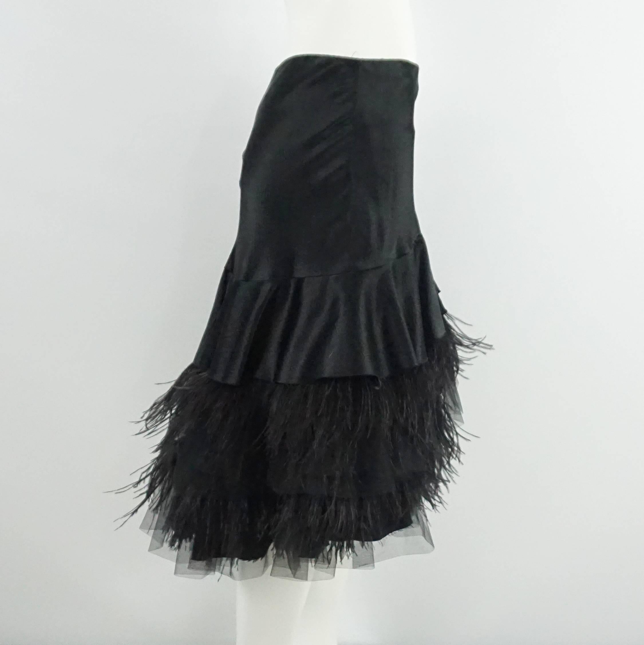 This Tuleh black skirt is high-low style and features a tight fit with ruffles of silk, tulle, and ostrich feathers on the bottom. The skirt is in excellent condition with minimal wear. Size 6, circa 21st Century. 

Measurements
Waist: 30