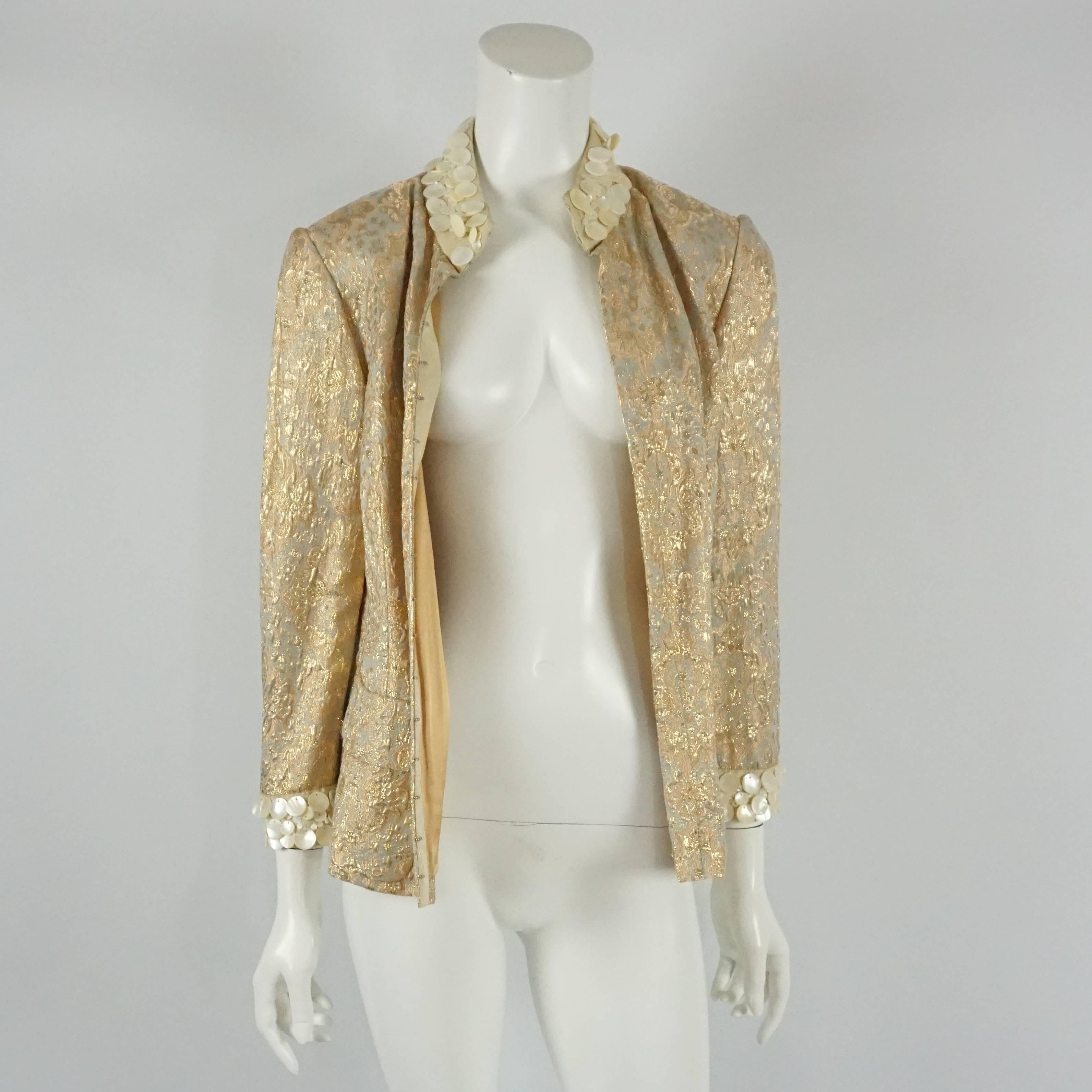 Dolce & Gabanna Silk Gold Brocade Jacket with mother of pearl trim - 44  This spectacular jacket is a must have for every fashionista. The fabric of the jacket has a light sage background with gold and rose gold detail, the cuffs and neckline have a