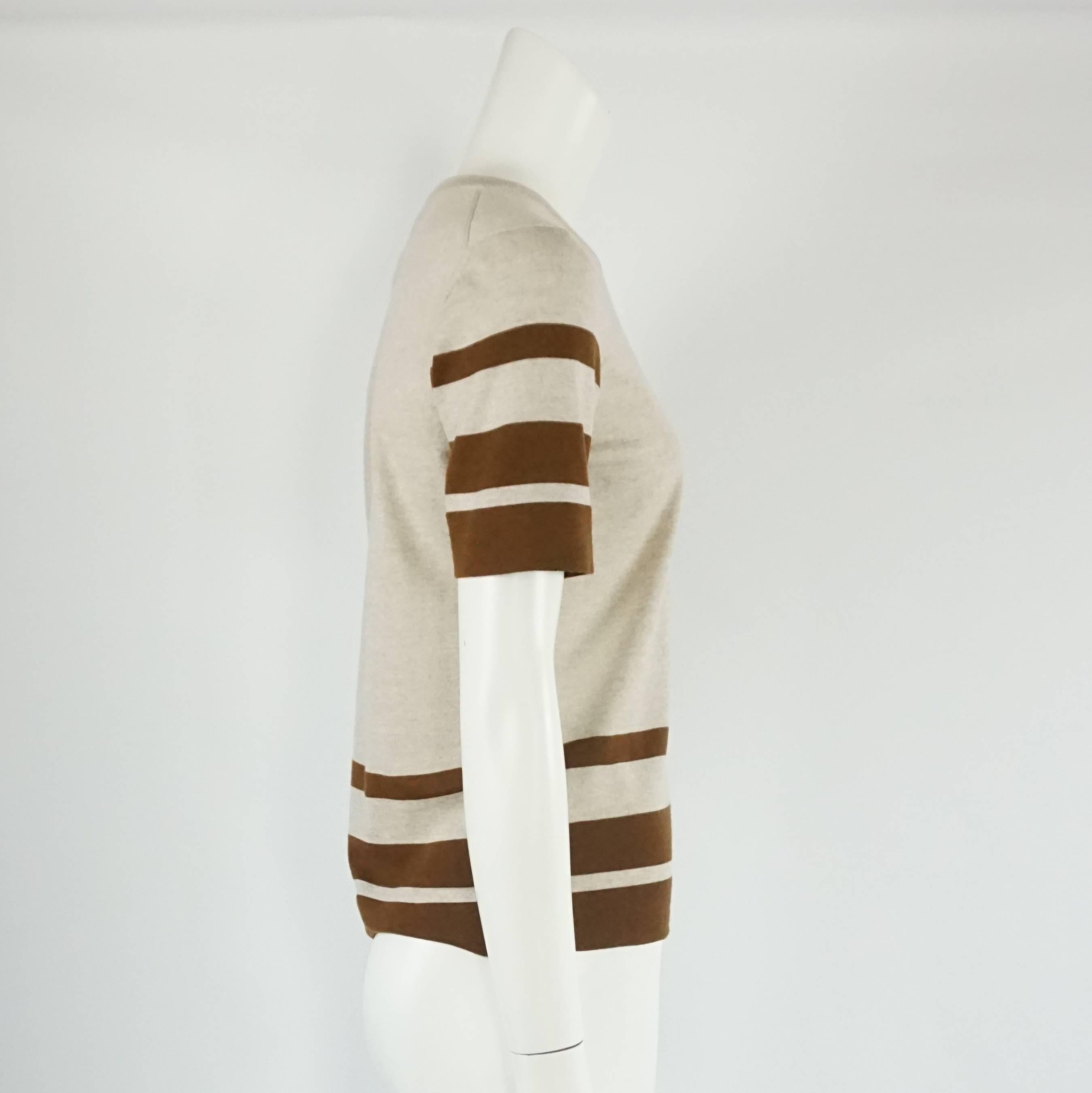 This Salvatore Ferragamo grey and brown virgin wool top has a classic-equestrian feel. The blouse is round necked with stripes on the sleeves and bottom and a small Ferragamo metal logo on the bottom. The piece is in excellent condition with a