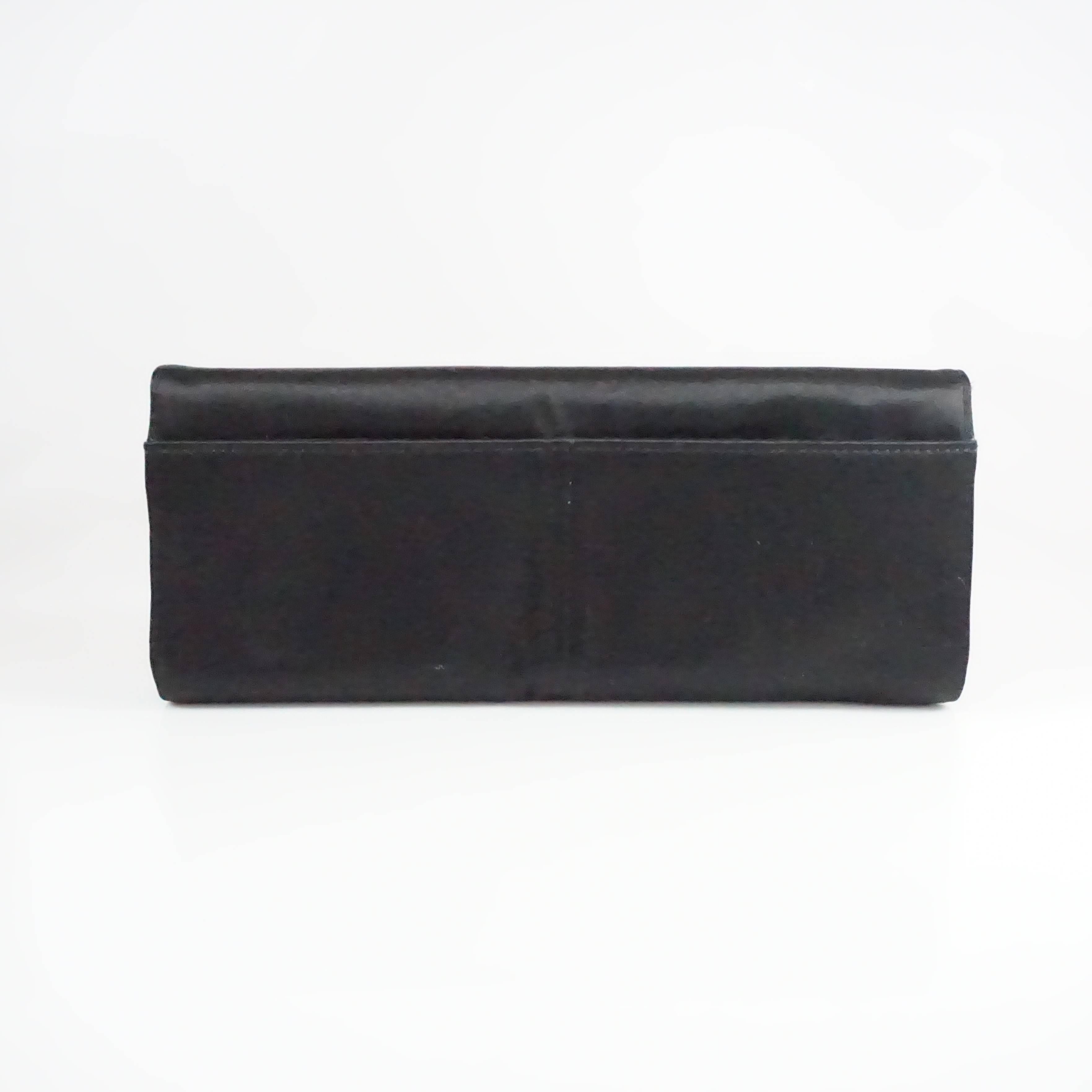 This Stuart Weitzman bag is made of black satin with dark brown stones all along the front. The bag can be used as a clutch or shoulder bag and comes with 2 back pockets, 1 interior zip pocket, and a magnetic closure. It is in excellent condition