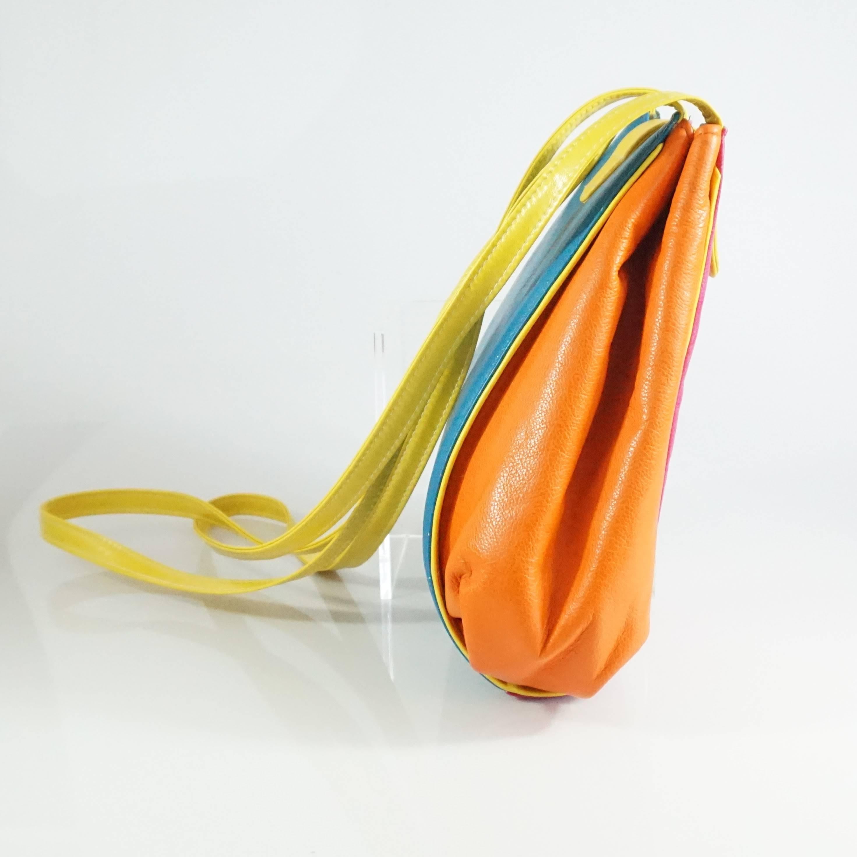 This vintage cross body bag is the perfect pop of color. It is made of leather and features a snap closure, an accordion style opening, white leather lining, and one small zipper compartment. The bag has yellow, orange, pink, green, blue, and purple