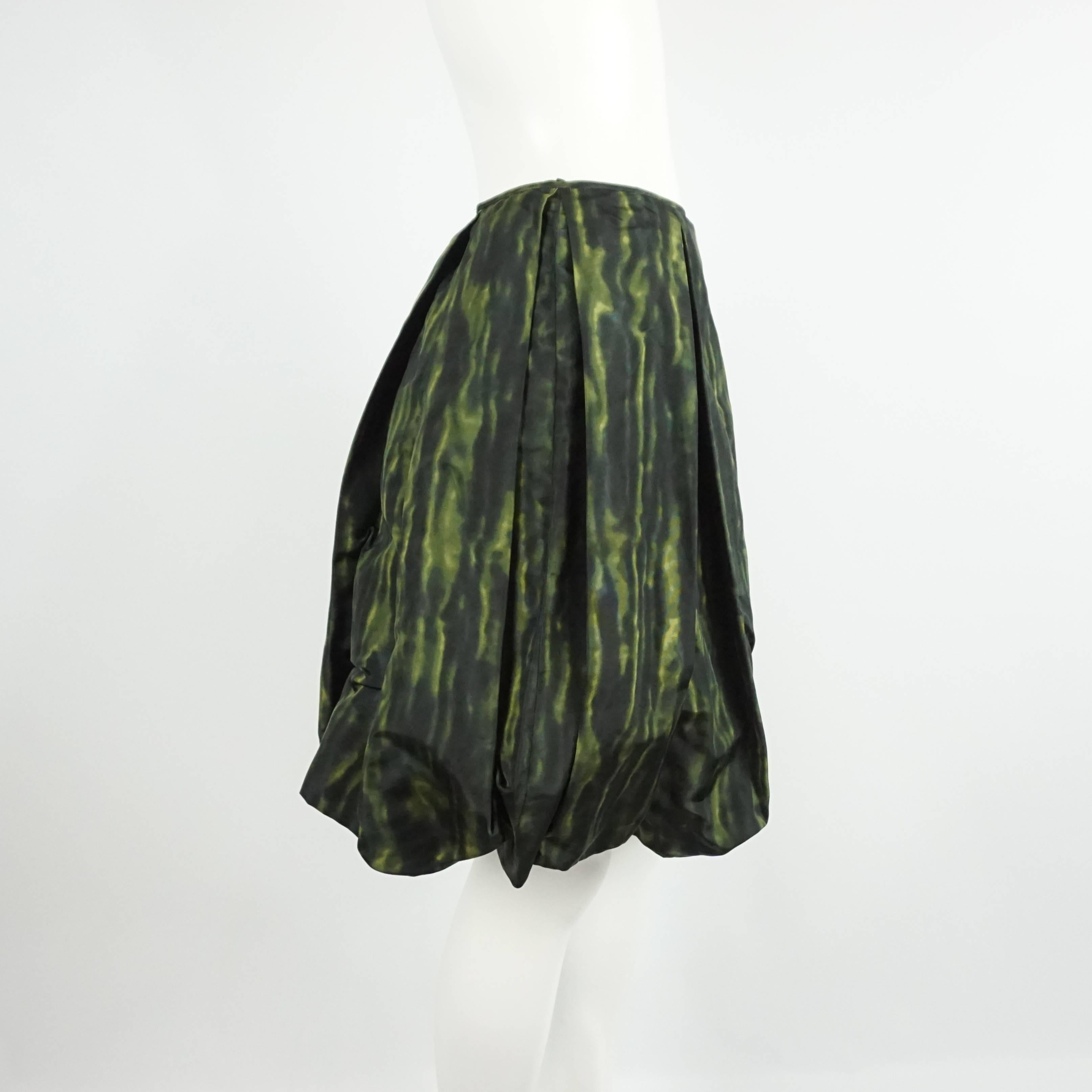 This Prada skirt is a great transition piece from summer to fall. It features a print in different hues of green, a bubble style, and large pleats. The silk taffeta skirt is in excellent condition with minimal wear. Size 44, circa 21st Century.