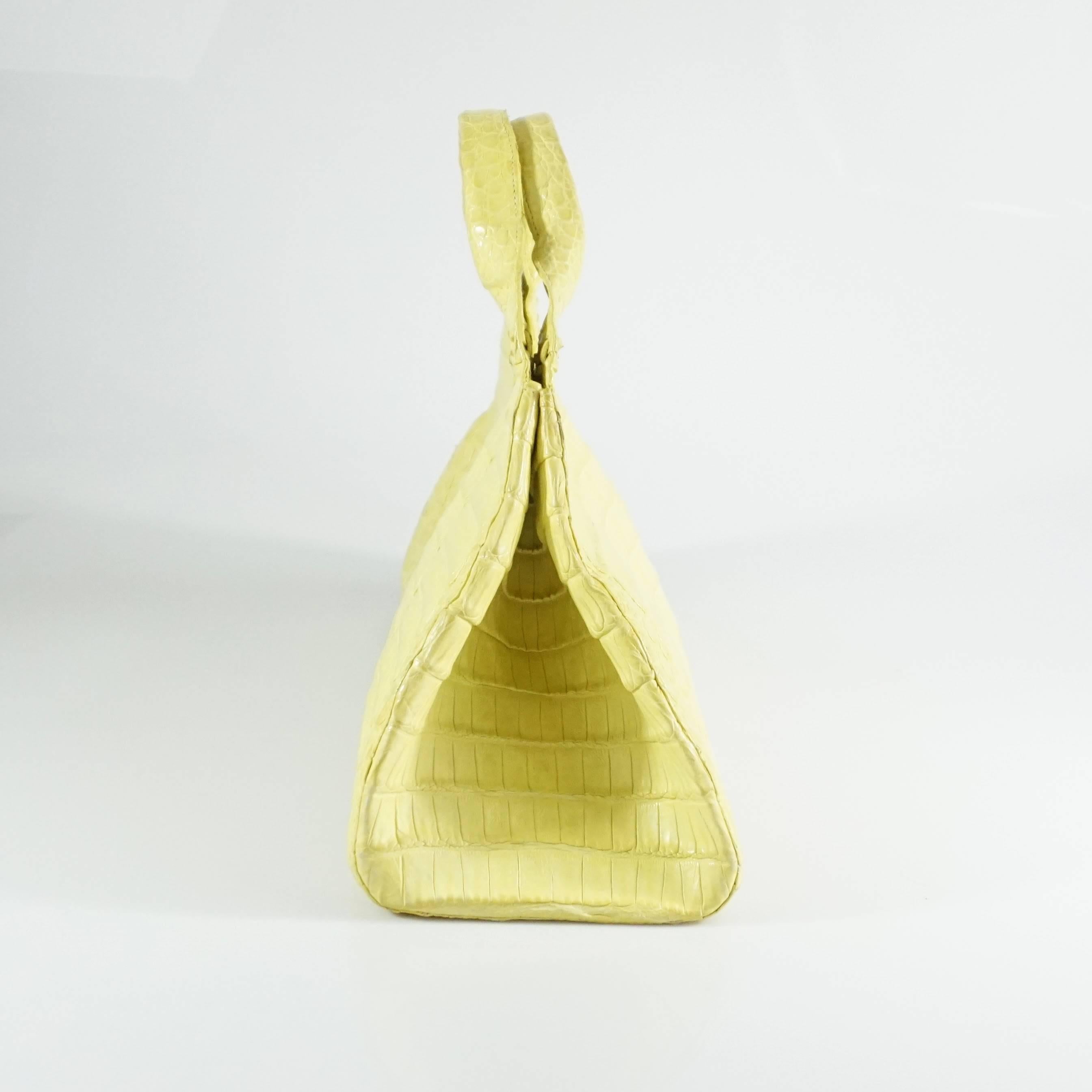 This Nancy Gonzalez yellow crocodile bag features a magnetic clasp, suede lining, 3 interior pockets, and comes with a duster. The bag is in good condition with some small markings and a couple areas where the color has chipped off. 