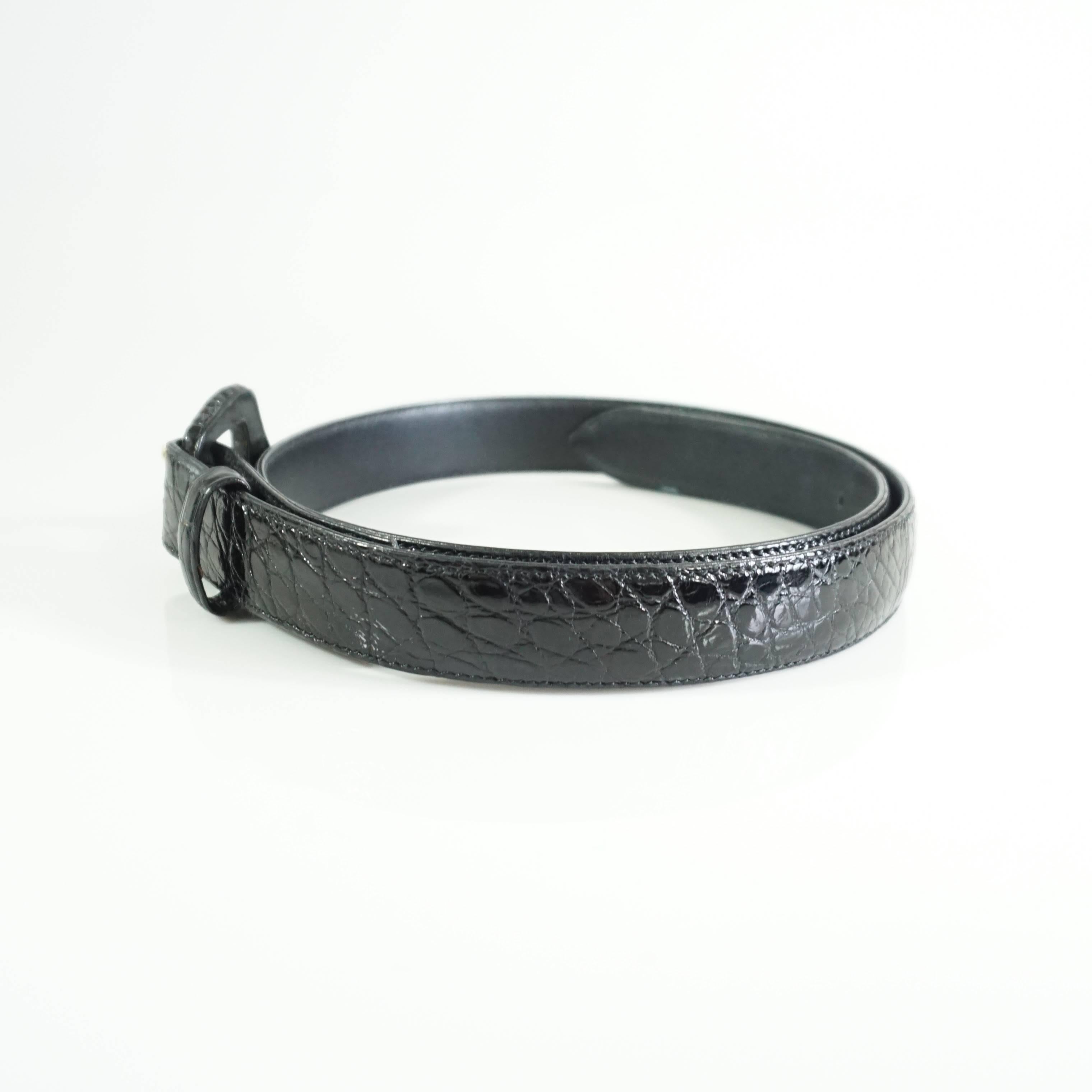 This Lana Marks black alligator belt has a sleek look. The entirety of the belt is alligator with the exception of the gold belt hook. The piece is in good condition with a couple small areas near the buckle that have blemishes (see the last