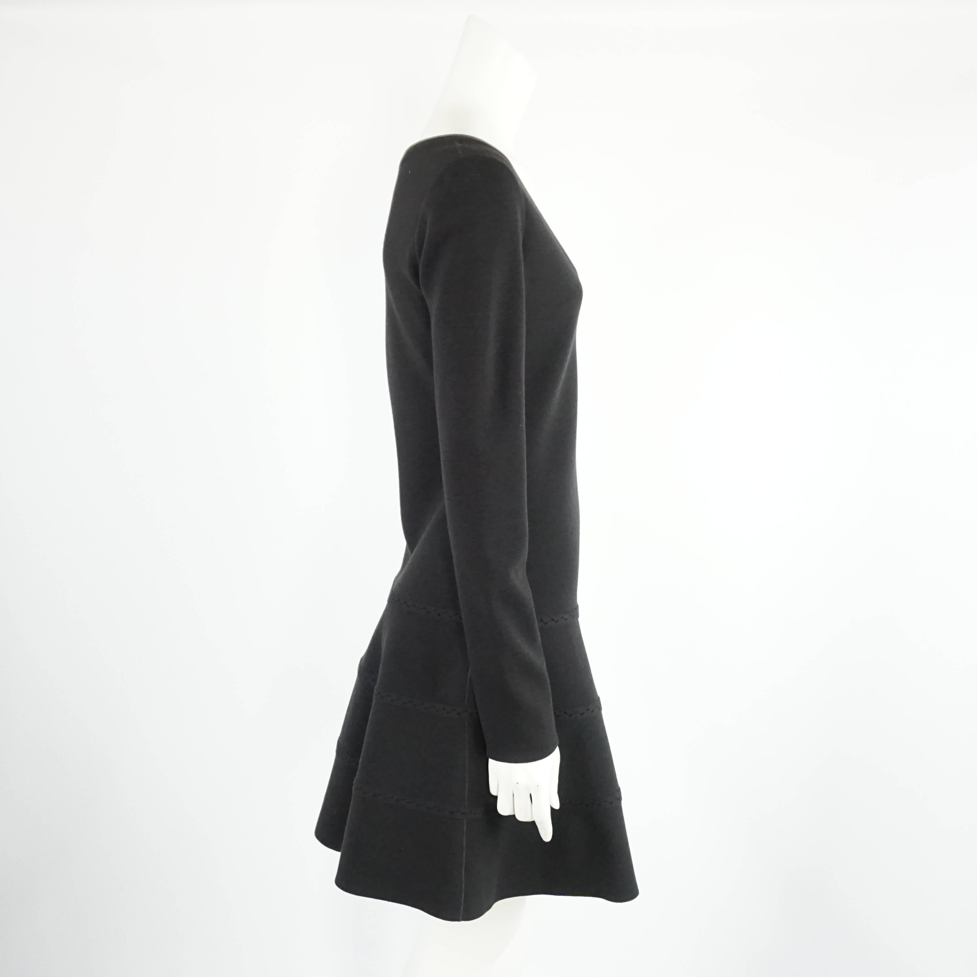 This Azzedine Alaia dress is a staple for fall and winter. The dress has a classic shape and features a v-neck, flare skirt, and knit detail on the bottom. It is in excellent condition with minimal wear. Size L, circa 21st century.