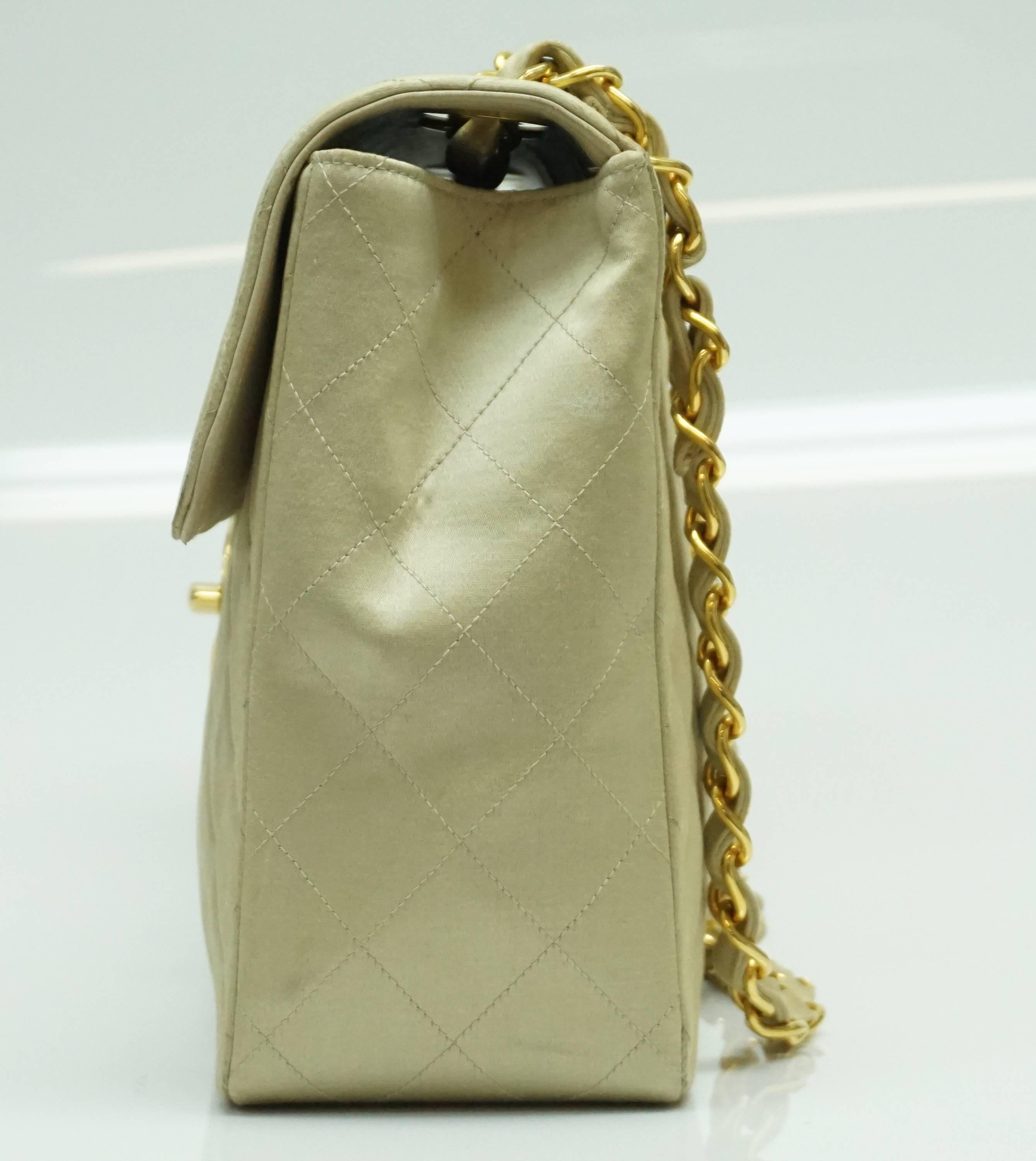 Chanel Gold Fabric Maxi Single Flap Handbag - GHW - Early 90's  This classic chanel handbag is in a very unique light gold fabric. The inside is fully leather. It has gold hardware. It has a minor chip/peel area in the CC and therefore we priced it
