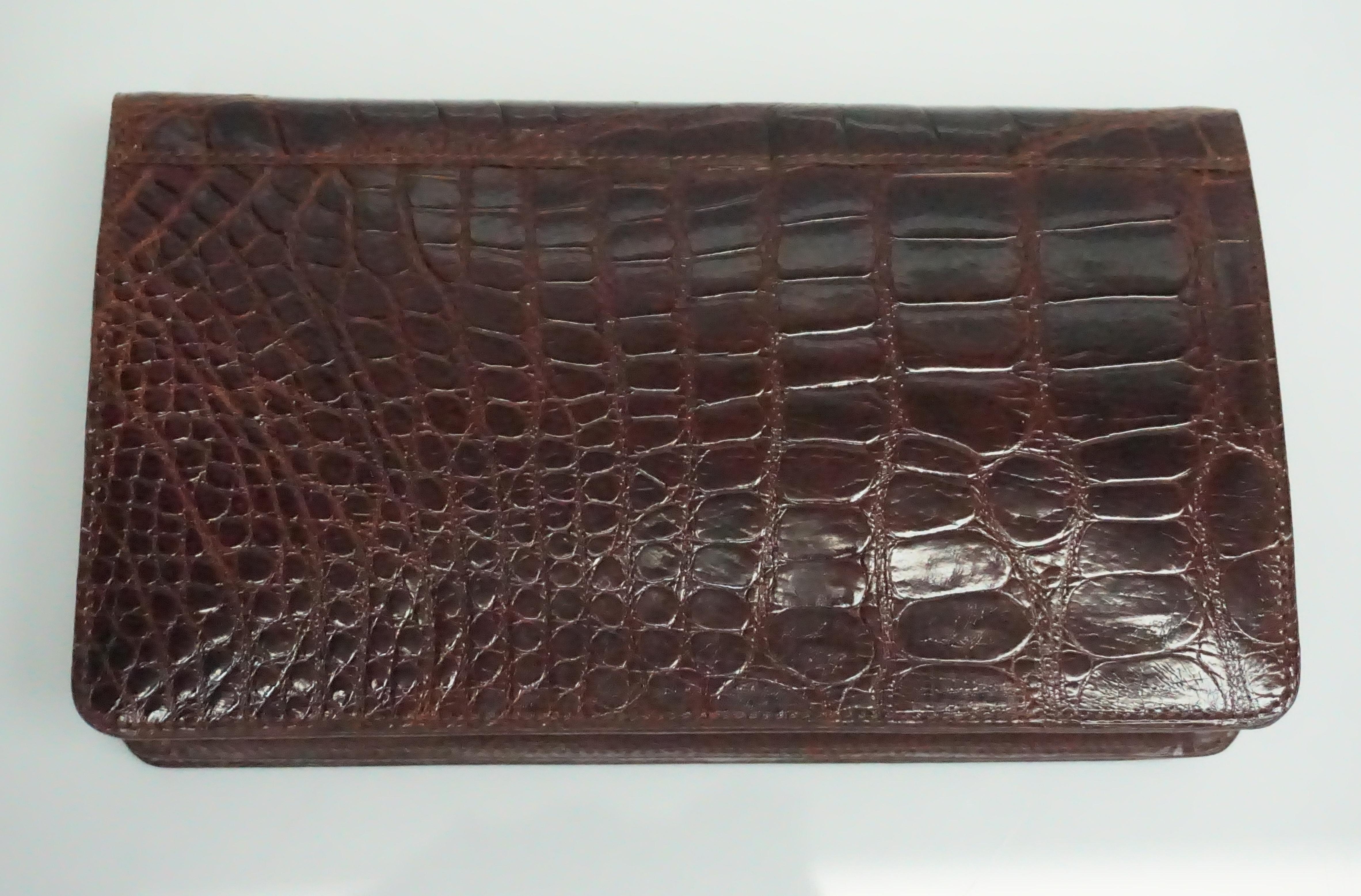 Saks Fifth Avenue Maroon Alligator Clutch  This beautiful alligator clutch is in excellent condition. The flap that opens and closes the clutch is detailed with a magnetic button. The inside of the clutch has one side pocket that closes with a