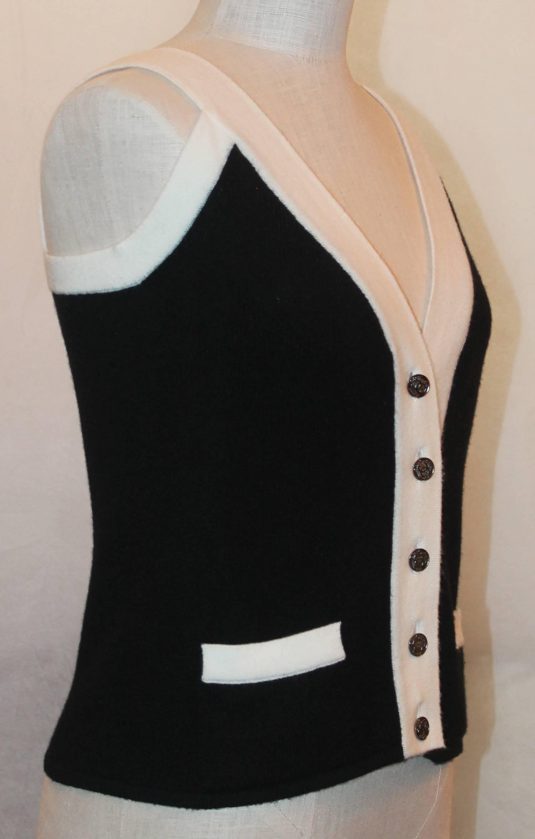 Chanel Sleeveless Black Cashmere Tank w/ Ivory Trim - 40 This tank top is in excellent condition. It has two front pockets that are trimmed with ivory. It also has silver enamel  buttons with classic 