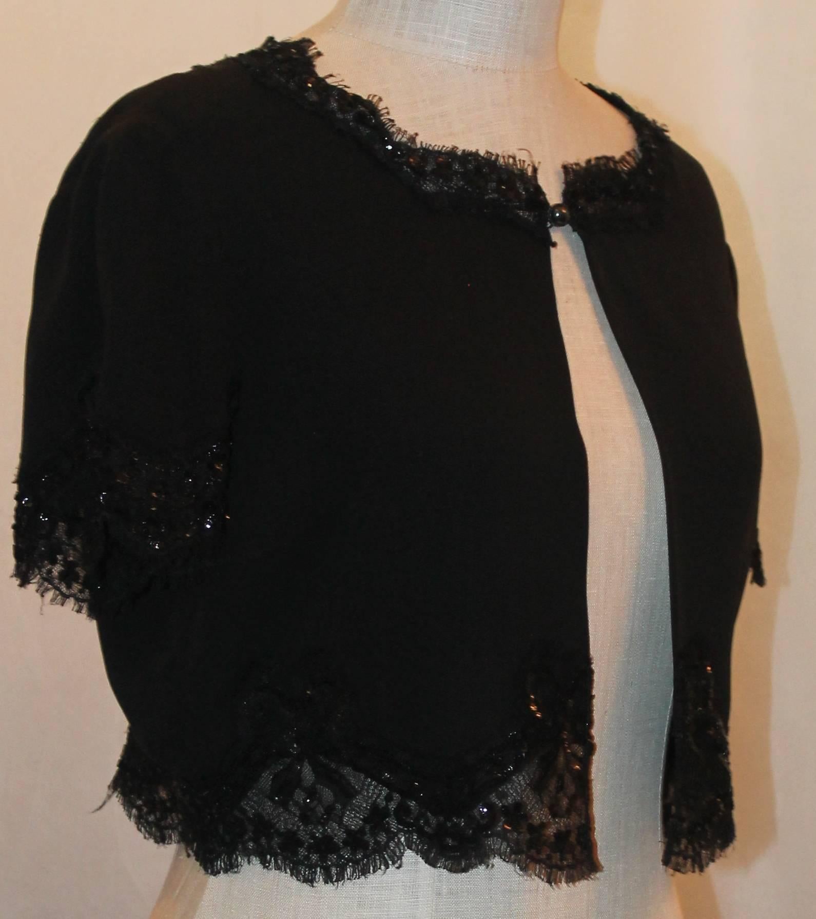 Chanel Black Silk Short Sleeve Bolero w/ Lace & Sequin Trim - 40.  This beautiful bolero has intricate lace and sequin detail along the trim.  it has one single button at the top center w/ a charcoal colored pearl w/ the "CC" mark on