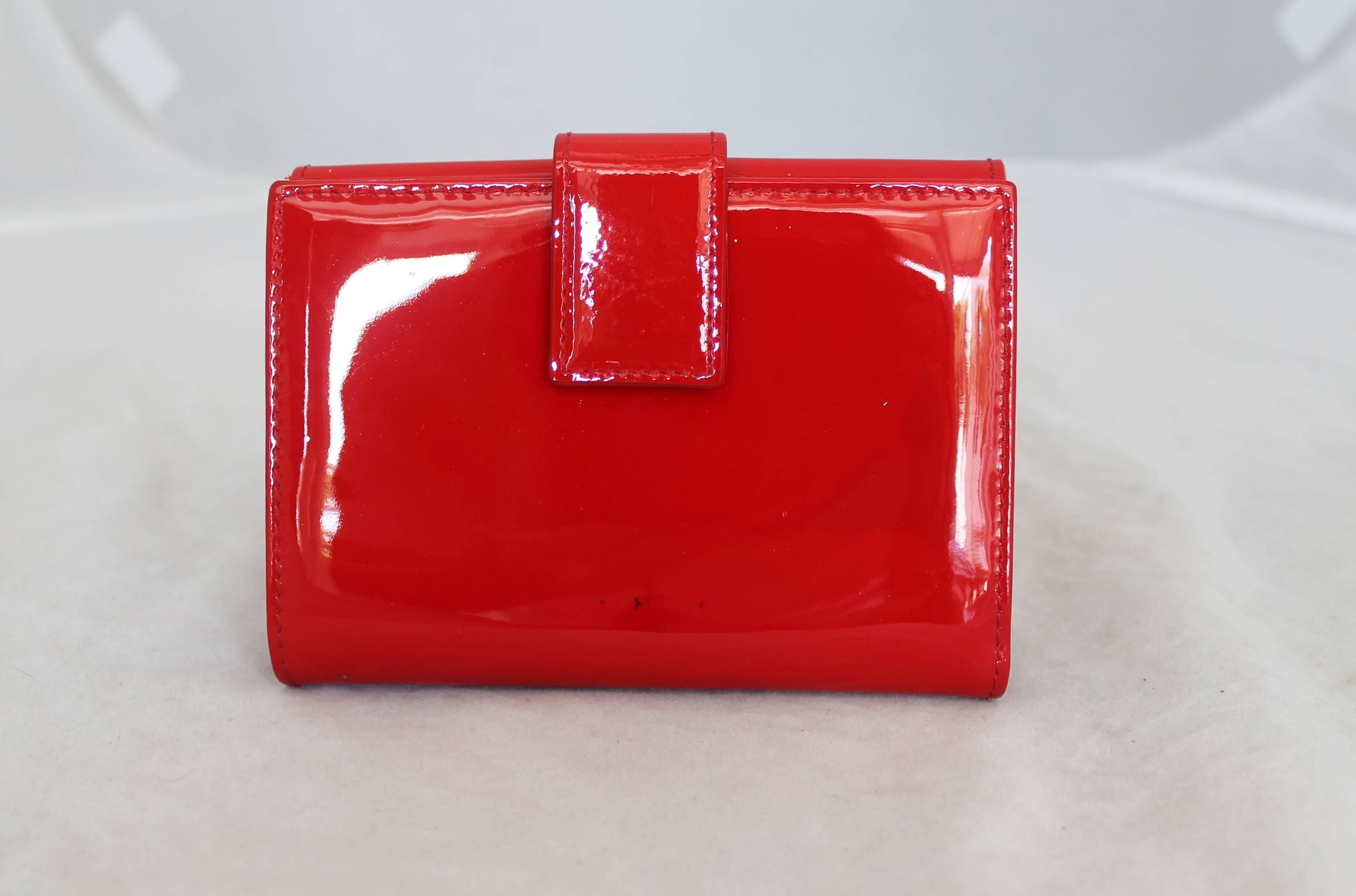 Christian Dior Red Patent Wallet SHW.  This wallet is in good condition; it has one small black mark on the back side near the bottom.  It has a front coin pocket, and on the back, it contains 10 credit card compartments, one I.D. slip, and two