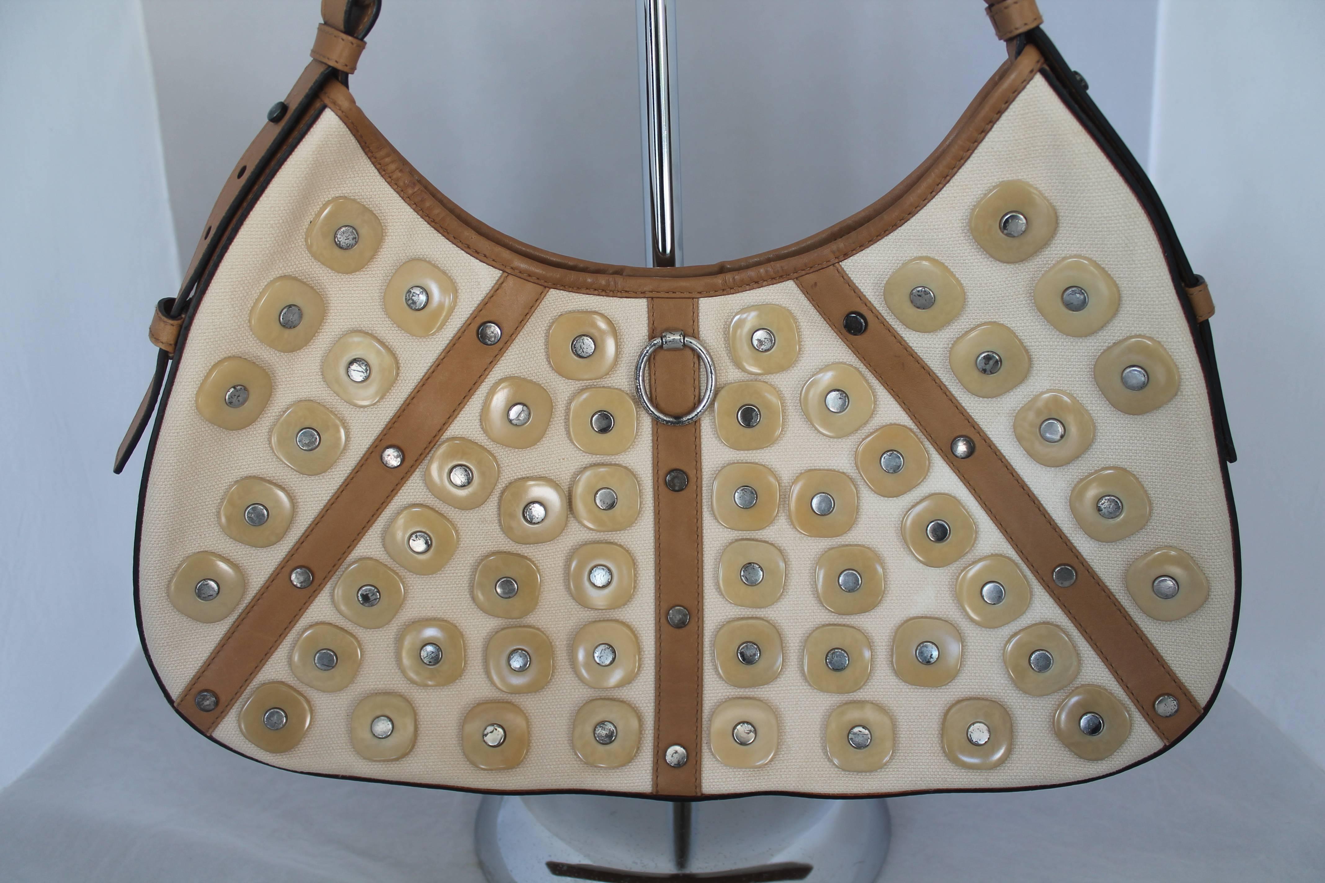 Yves Saint Laurent Beige Canvas Shoulder Bag w/ Enamel & Silver Studs. It also has luggage color and leather trim and handle. This bag is in fair condition. It has staining on the back of the bag, the paint on the silver studs is chipped, the