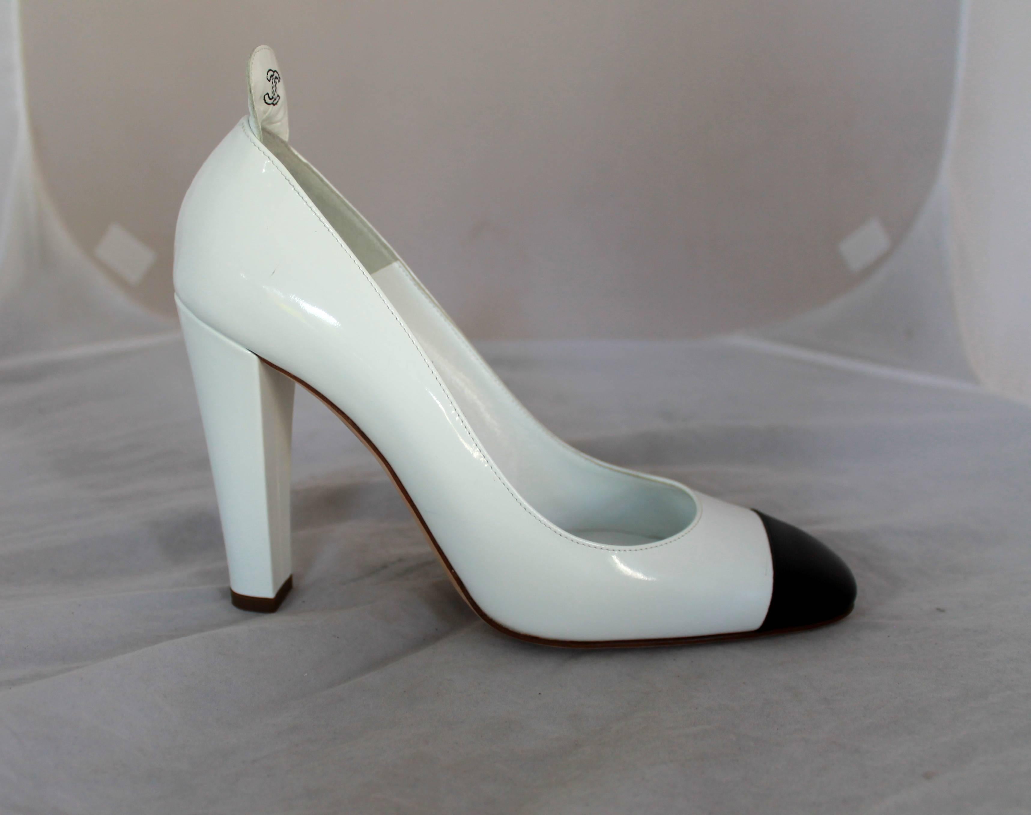 Chanel White Patent Pumps w/ Black Toe & Thicker Heel - 40.  These pumps are in excellent condition, they have minimal wear on the sole.  These pumps have a black patent toe and a back flap with black 