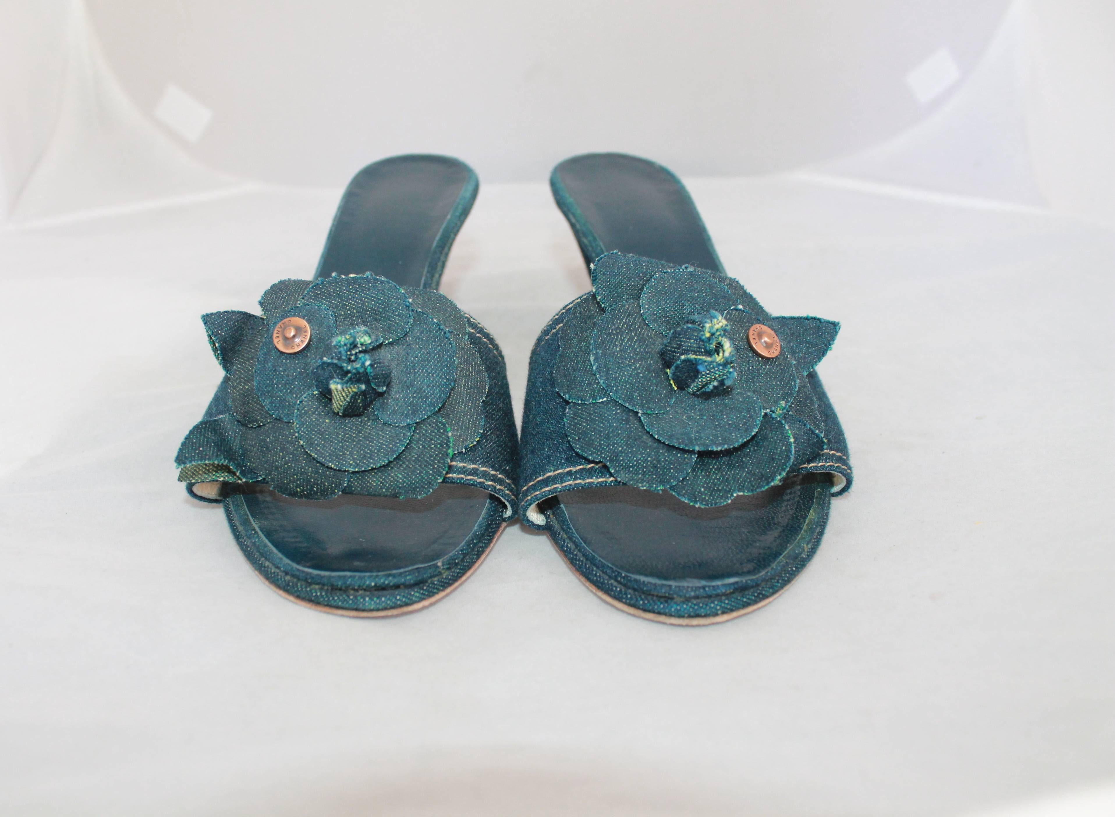 Chanel Blue Denim Slides w/ Camellia & Chanel Rivet - 40.  These slides are in excellent condition with wear to the sole.  They are made of a denim material, as are the Camellias.  They have a copper-looking rivets with 