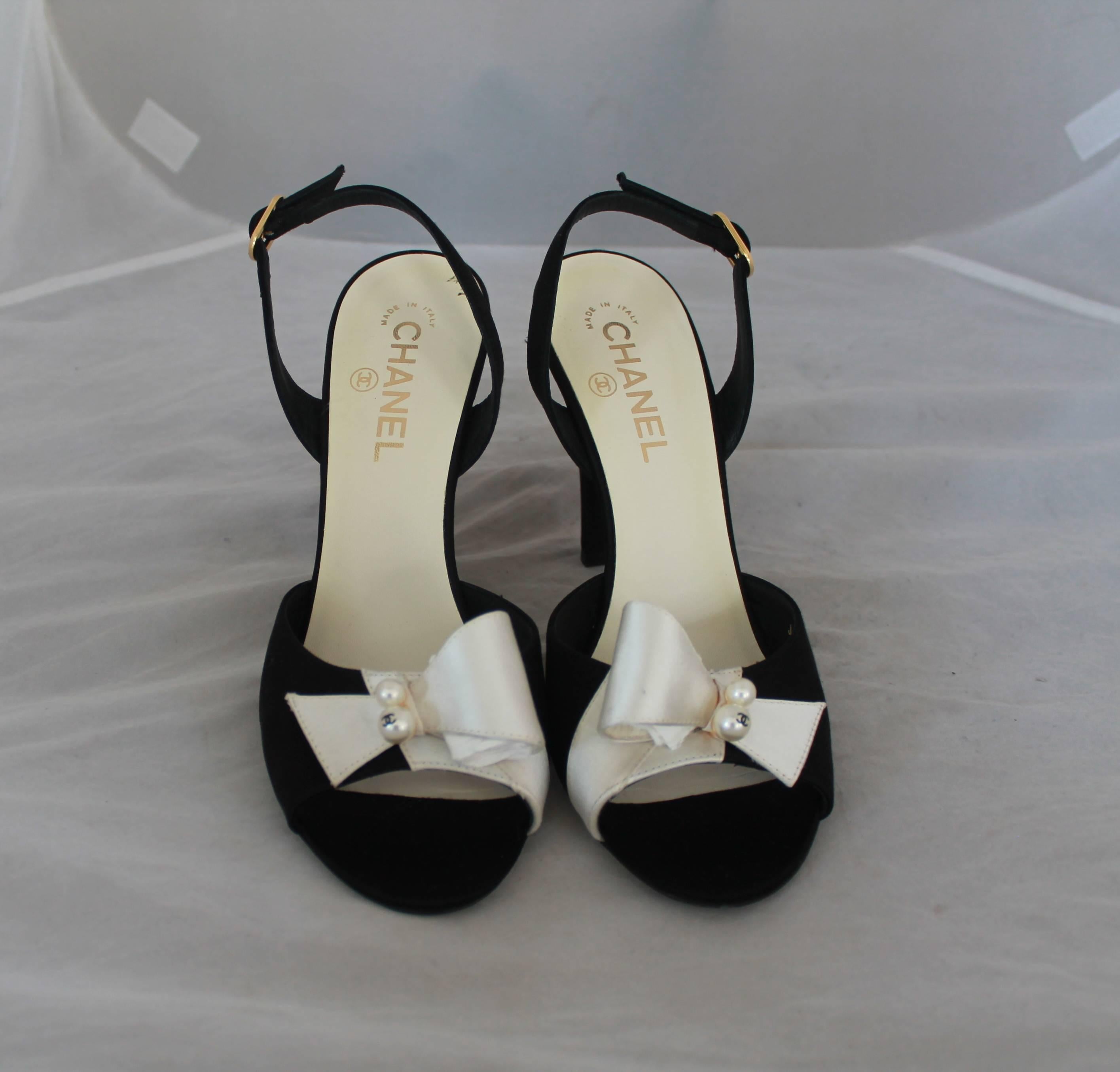 Chanel Black & Ivory Satin Open-Toe Sling Back Sandals w/ Front Bow - 40.  These elegant sling back sandals are in very good condition with minor bottom wear, a small mark on the right shoe near the heel as shown in Image 4, and a slight orange