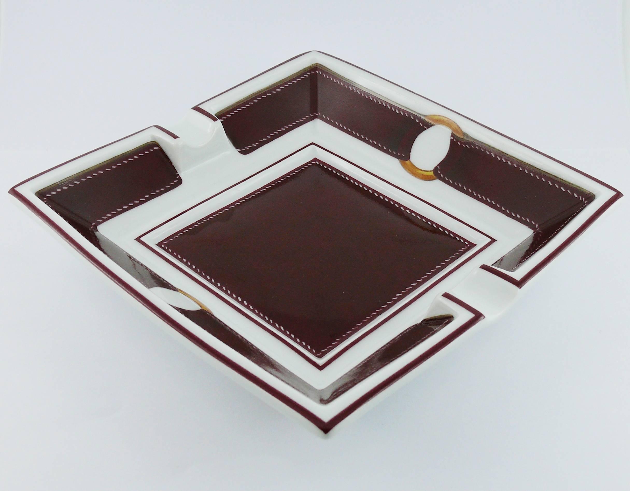 HERMES gorgeous square porcelain ashtray/pin tray featuring a burgundy leather with saddle stitching trompe-l'oeil design.

Marked HERMES Made in France.

Indicative measurements : length approx. 15.8 cm (6.22 inches) / width approx. 15.8 cm