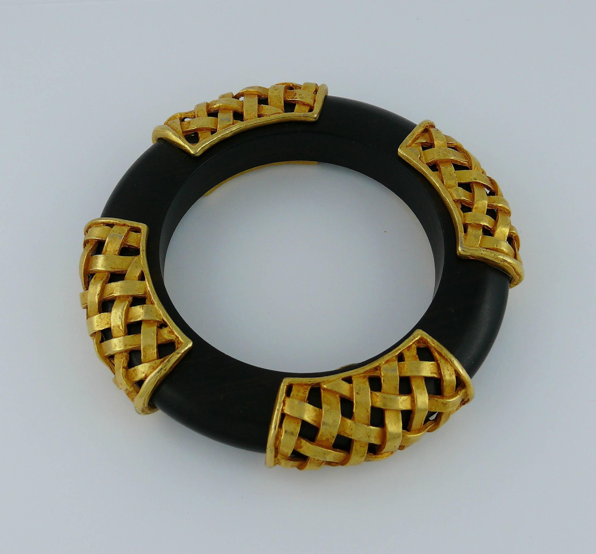DOMINIQUE AURIENTIS vintage massive wooden bangle decorated with four braided gold-tone caps.

Marked DOMINIQUE AURIENTIS Paris.

Indicative measurements : inner circumference approx. 19.79 cm (7.79 inches) / width approx. 1.2 cm (0.47