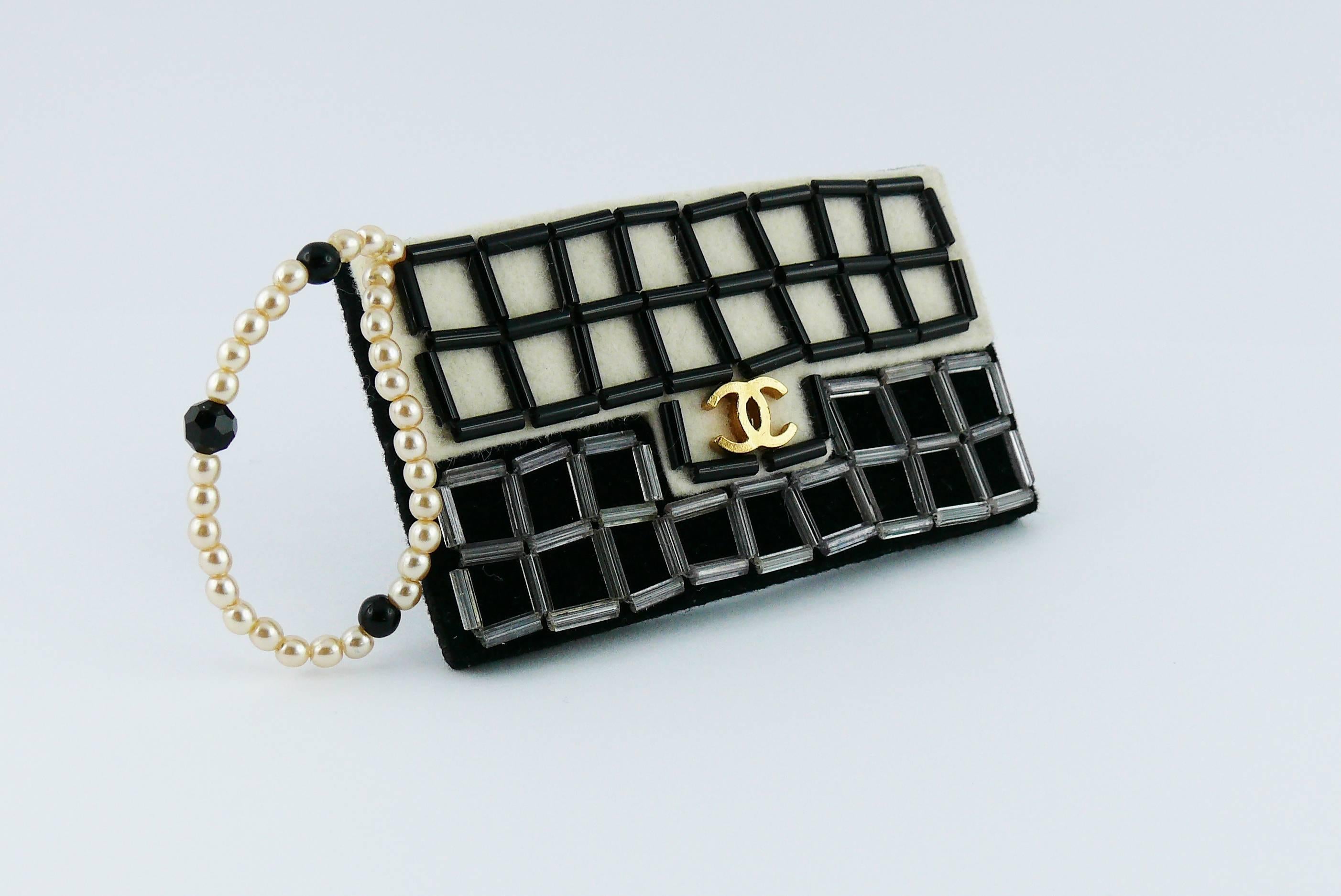 CHANEL large iconic 2.55 bag felt brooch featuring a faux pearl strap, glass beads and gold toned CC monogram on front.

Fall/Winter 2002.

Bar pin fastening.

Marked CHANEL 02 A Made in France.

Indicative measurements : length approx. 7 cm (2.76