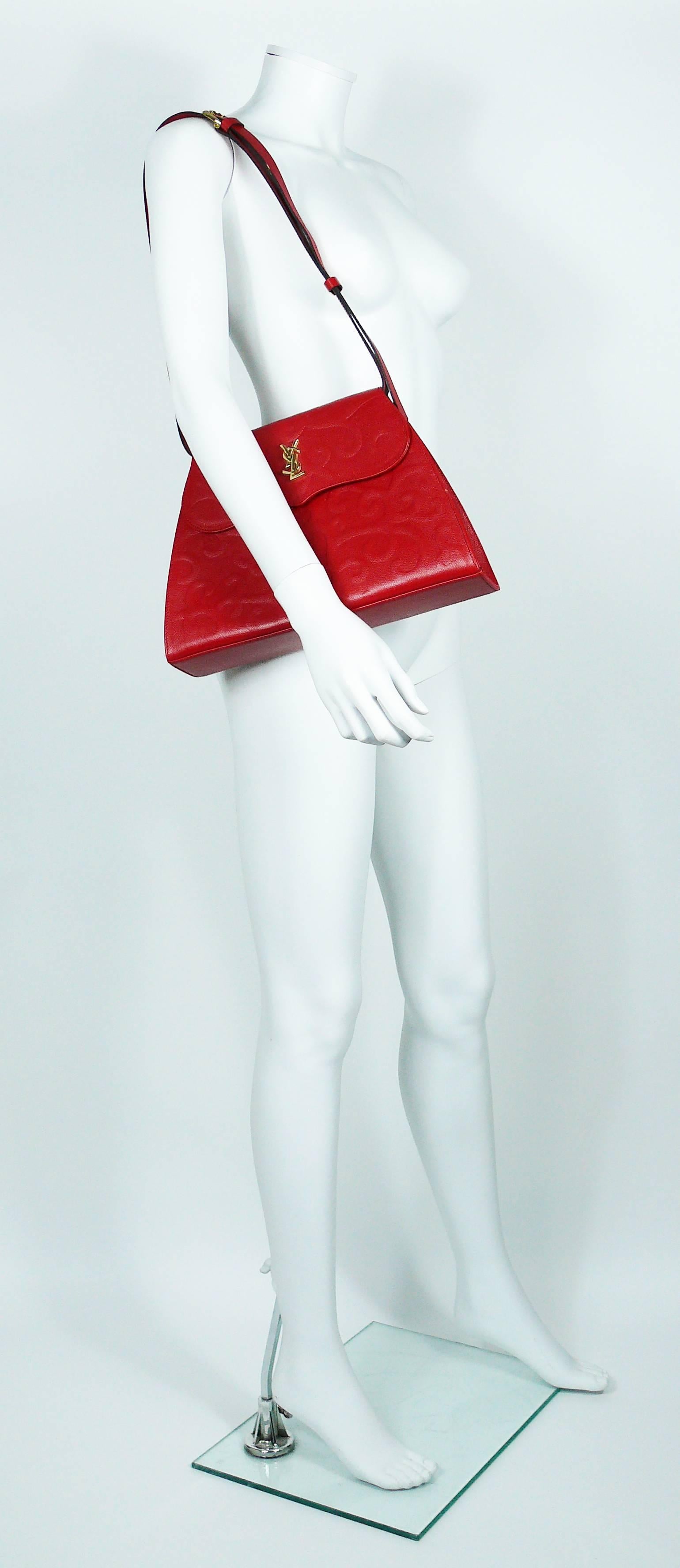 YVES SAINT LAURENT vintage red leather arabesque trapezoidal shoulder bag.

Grained leather featuring a gorgeous embossed arabesque design.

Gold toned YSL monogram logo on the front flap.

Removable shoulder strap that allows this bag to be used