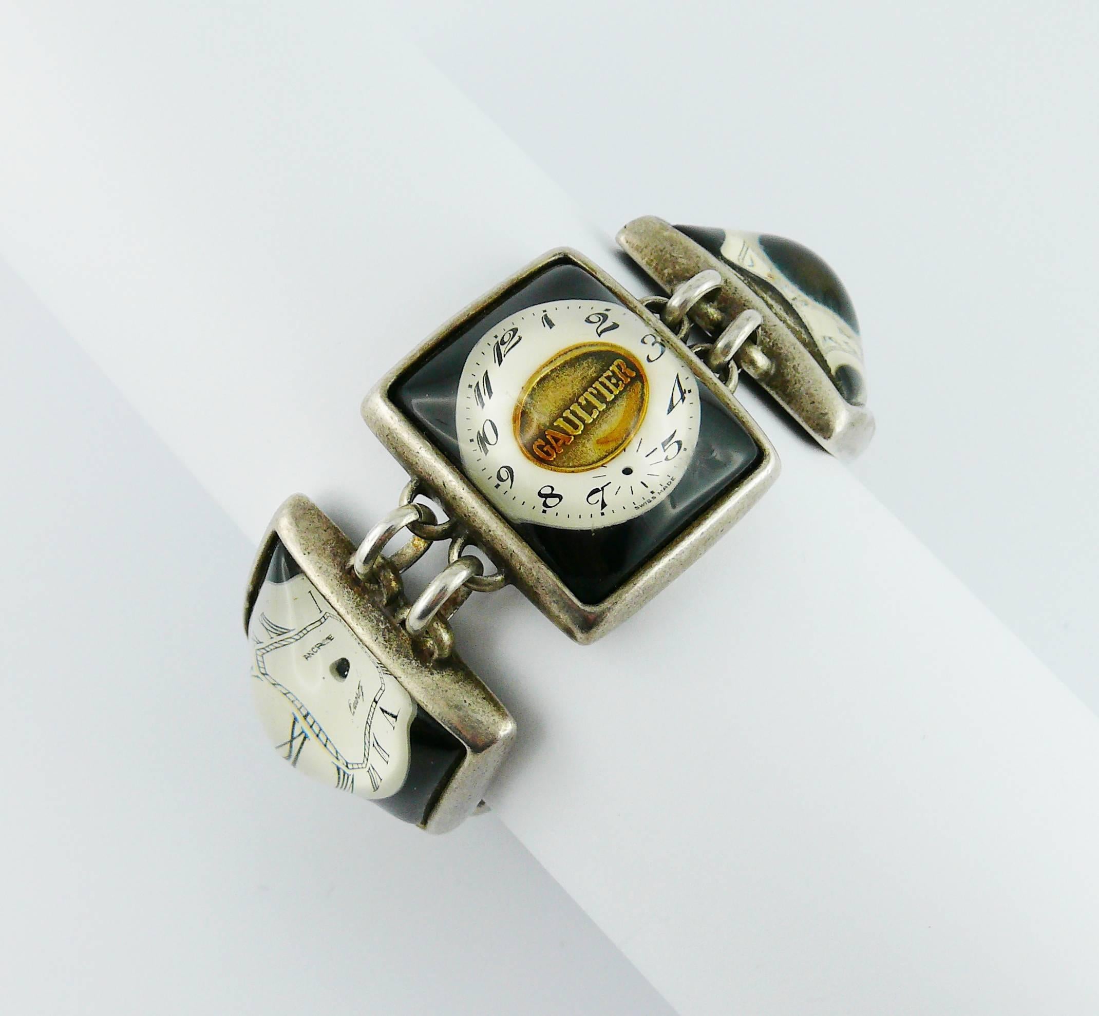 JEAN PAUL GAULTIER bracelet de montre vintage rare et de collection.

Maillons de couleur argentée avec patine présentant des cadrans de montre rectangulaires dans un dôme en résine transparente incrustée.

Marqué GAULTIER.

Mesures indicatives :