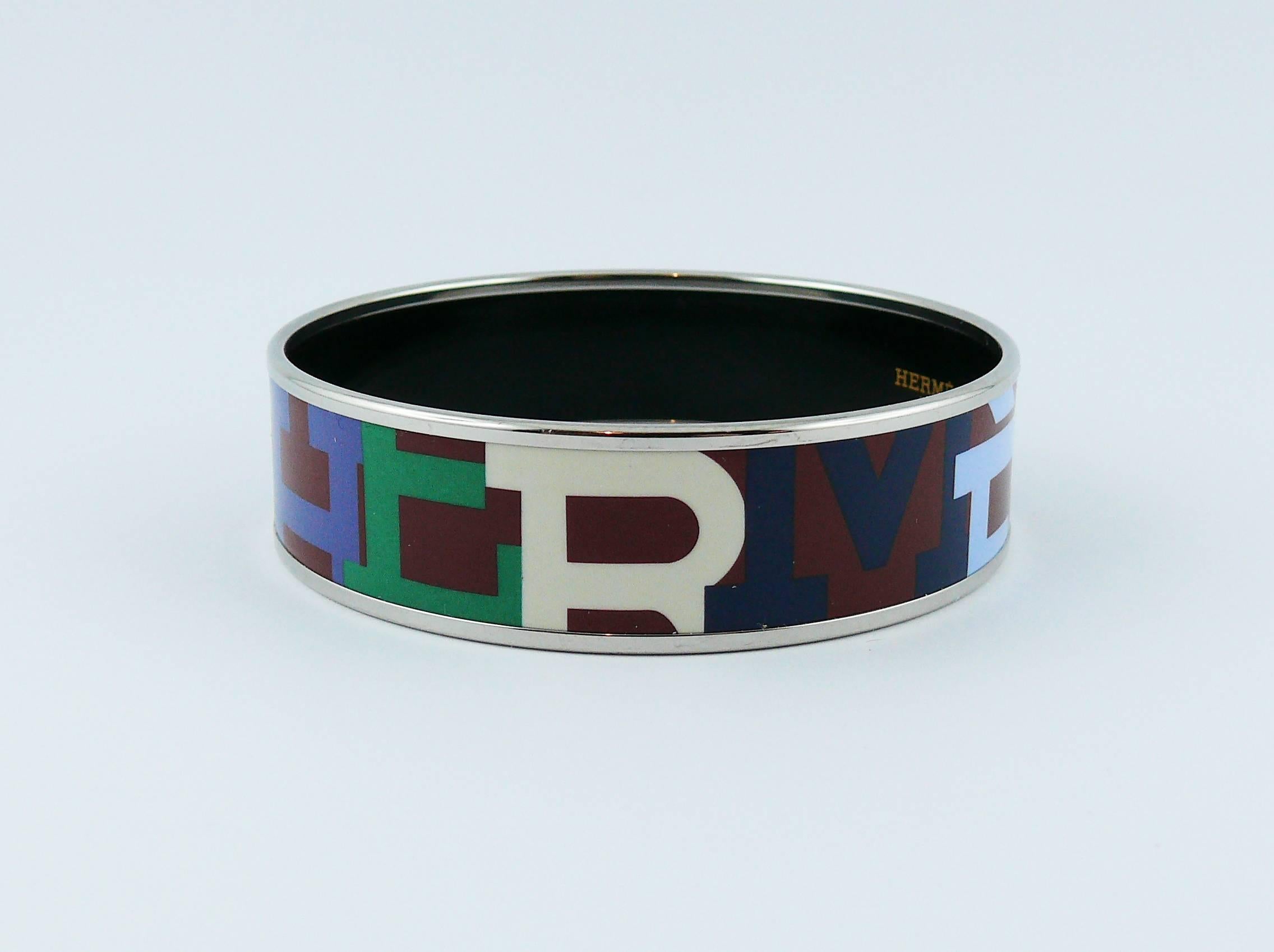 HERMES wide Capitales printed enamel bracelet featuring HERMES logo in blue, green and off-white on a burgundy red background.

Palladium plated rims.

Marked HERMES Paris.
Made in France + O.

Indicative measurements : total diameter approx. 7 cm