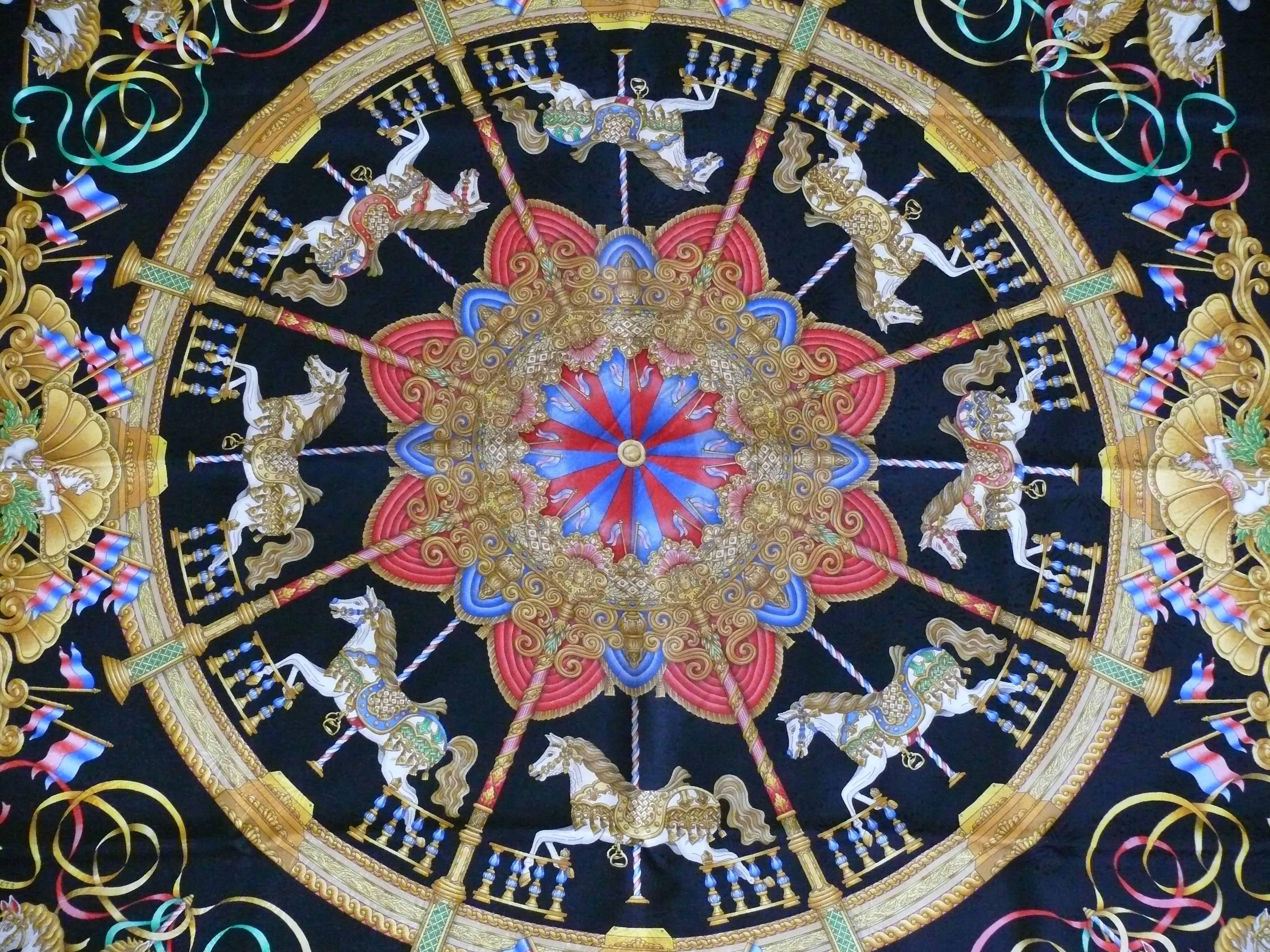 HERMES silk jacquard carré "Luna Park" featuring an opulent and multicolored intricated design of carousel horses on a black background.

First issued in 1993.

Designed by JOACHIM METZ.

This scarf features :
- Hand rolled borders.
-