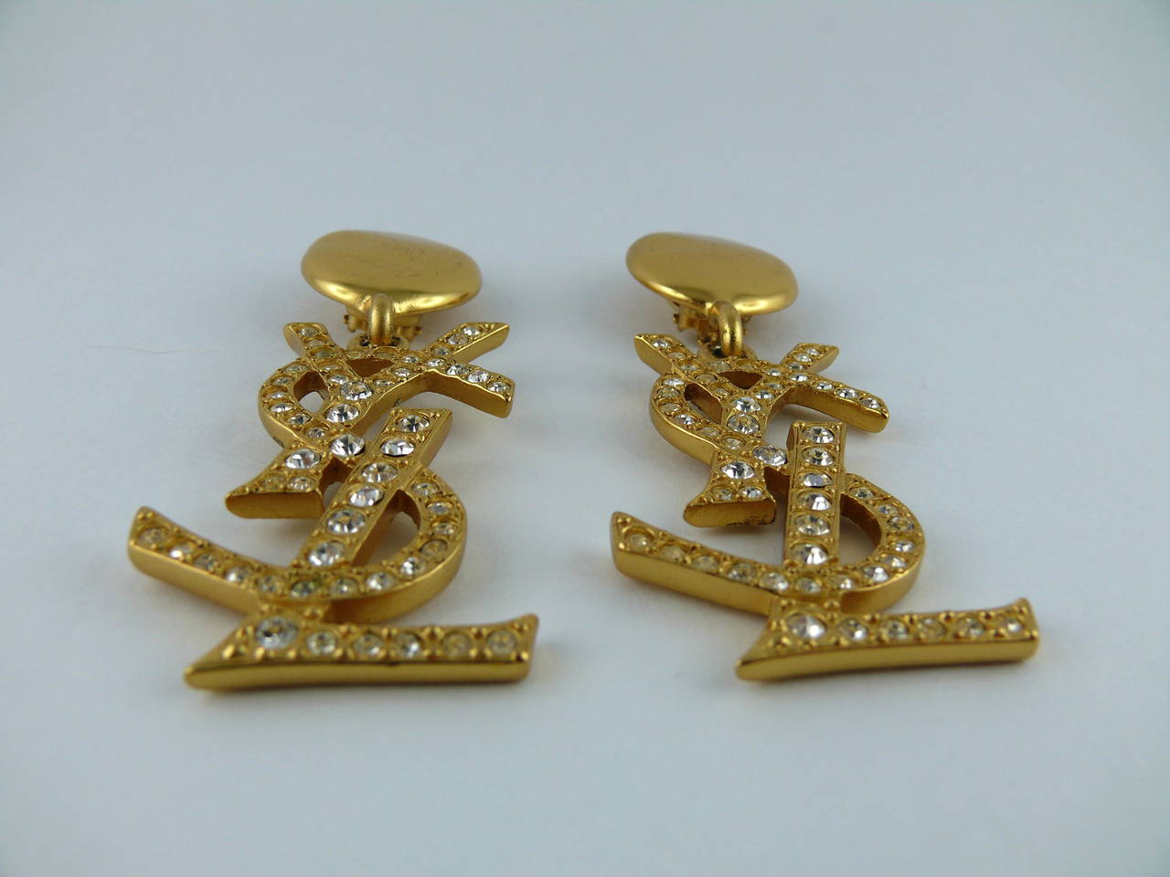 YVES SAINT LAURENT massive vintage gold tone and crystal iconic logo dangling earrings (clip on).

Rare and collectable item !
As seen on Samantha Jones in SATC 2.

Marked YSL Made in France.

Note
As a buyer, you are fully responsible for