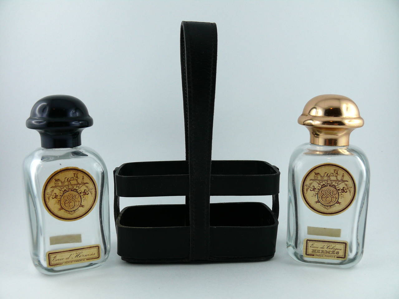 HERMES Paris ultra rare vintage perfume bottle holder in black box leather with black saddle stitch seam.

Set is complete including two empty "Eau d'Hermès" and "Eau de Cologne Hermès" small glass bottles.

Gold embossed