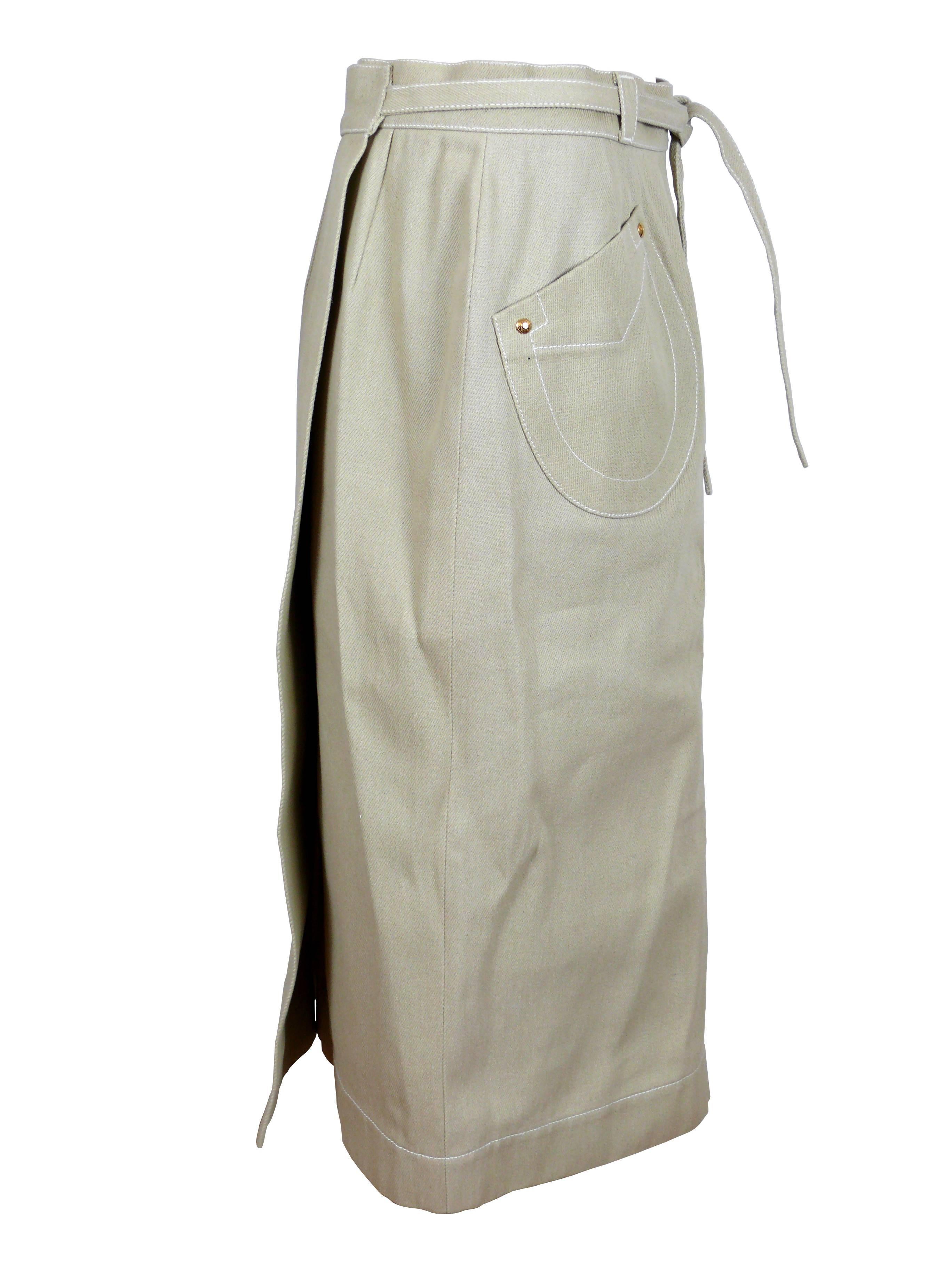 HERMES Paris wrap around natural cotton skirt.

Skirt attached with two buttons hidden in the waistband and a belt.
Two large asymetrical front pockets with white saddle stitch detail and gold tone 