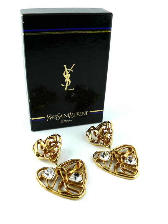 YVES SAINT LAURENT vintage massive jewelled wired heart dangling earrings.

Gold tone metal with heart shaped crystal embellishement.

Signed YSL Made in France.

Comes with original box.

JEWELRY CONDITION CHART
- New or never worn : item