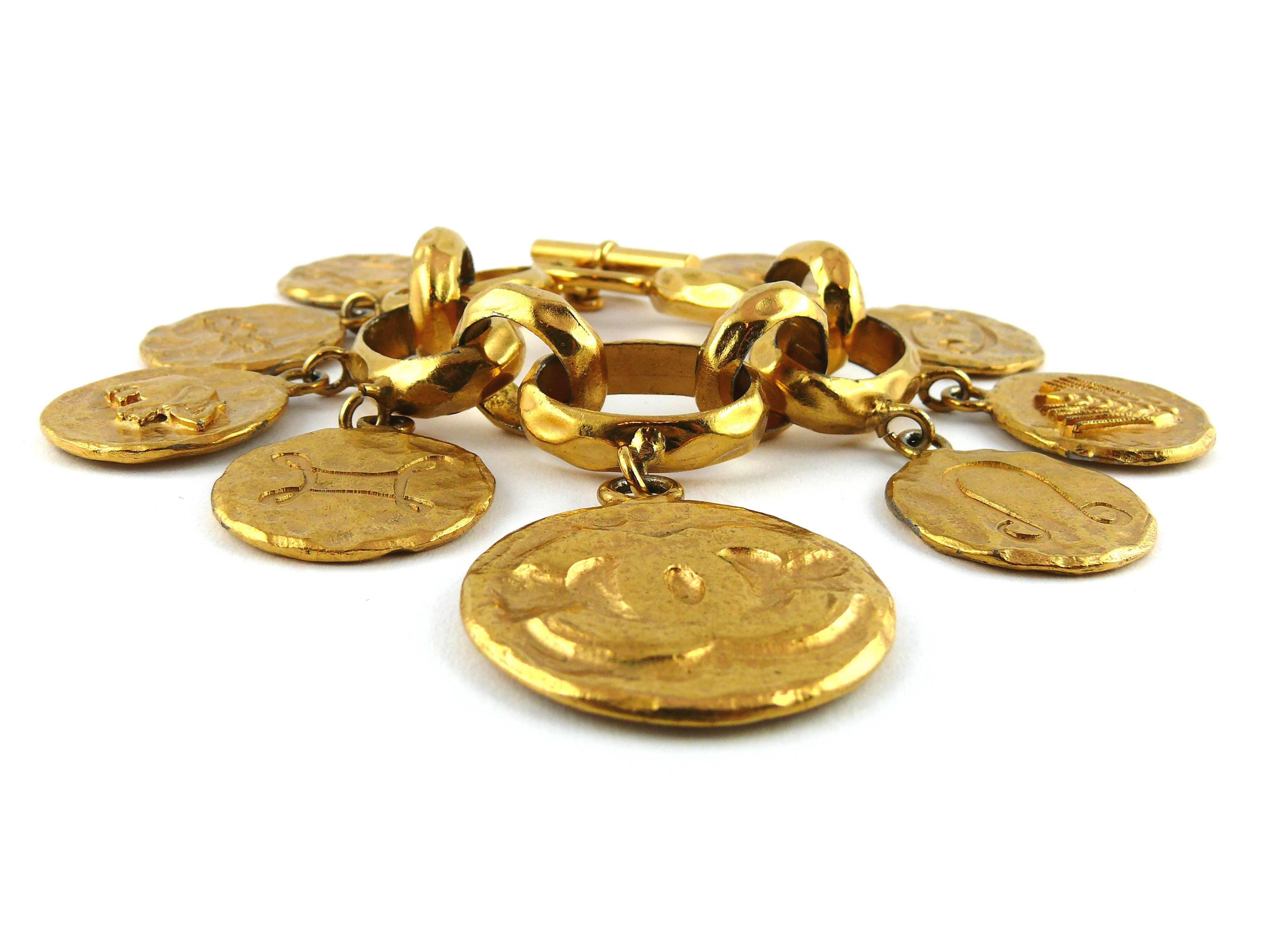 CHANEL vintage rare gold plated charm bracelet featuring 9 large coins and chunky hammered oval shaped links.

Charms feature zodiac signs, Coco Chanel profile, wheat, interlocking CC insigna, elephant.

T-bar and ring closure.

Has some