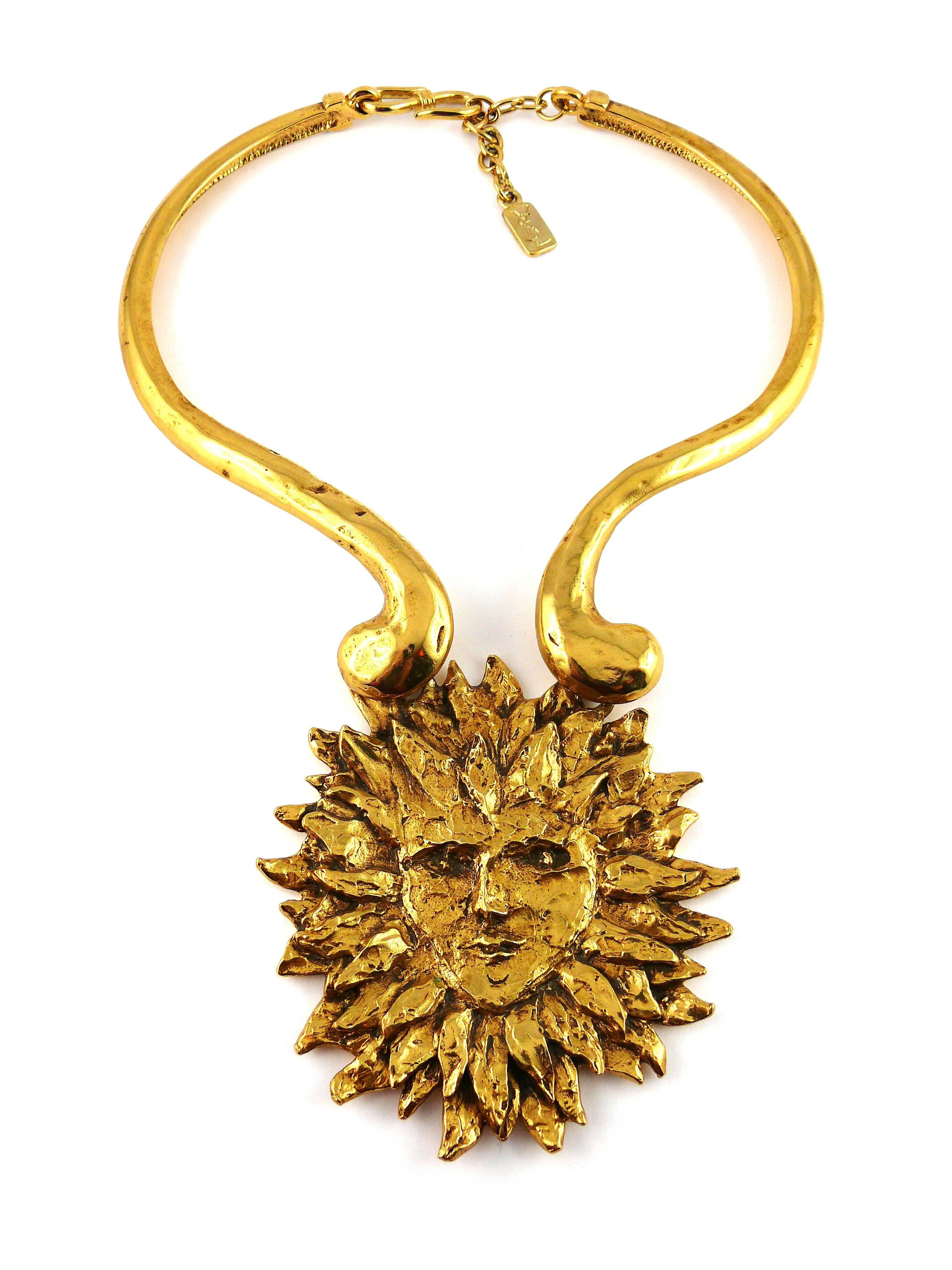 YVES SAINT LAURENT vintage rare gold tone sun face chocker necklace by ROBERT GOOSSENS, circa 1980s.

This necklace features a rigid collar and a massive 3D textured sun face pendant. Hook closure.

A similar example is part of the BARBARA