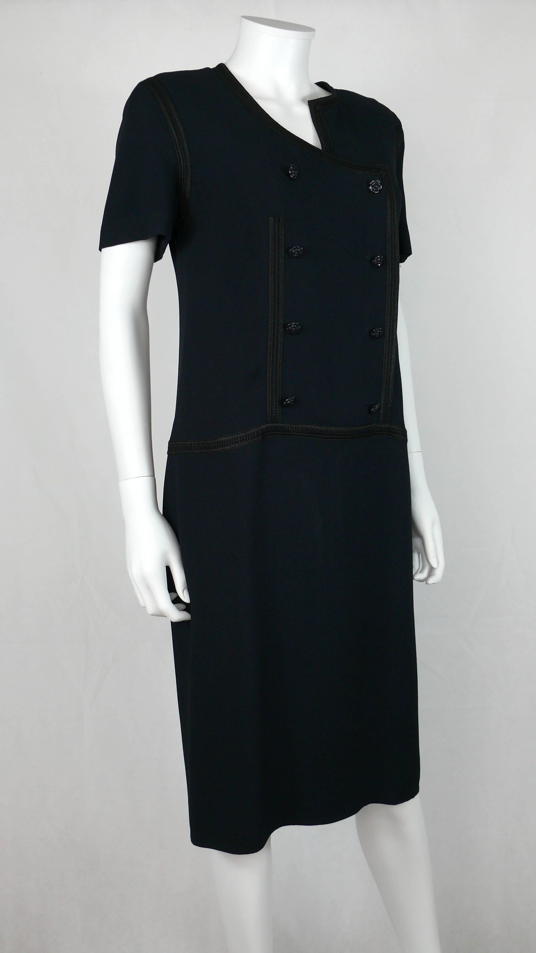 CHANEL 2002 Cruise Collection navy dress featuring an asymmetric collar, braids detail and enameled camelia buttons.

Fully lined.
Shoulder pads.
Back zip closure.

Label reads CHANEL Made in France.

Marked Size : 44.
Please refer to