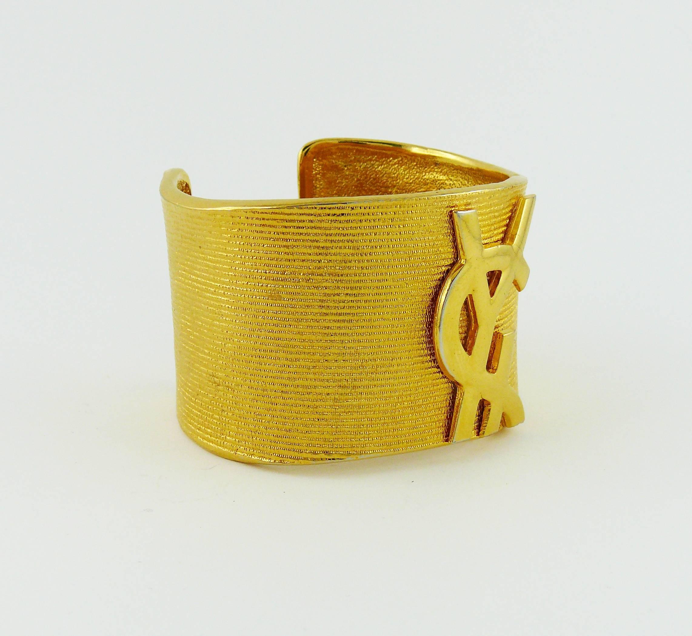 YVES SAINT LAURENT vintage gold tone ribbed textured cuff bracelet featuring a large signature logo at the front.

Embossed YSL Made in France.

Indicative measurements : inside circumference approx. 18.2 cm (7.17 inches) /  width approx. 4 cm