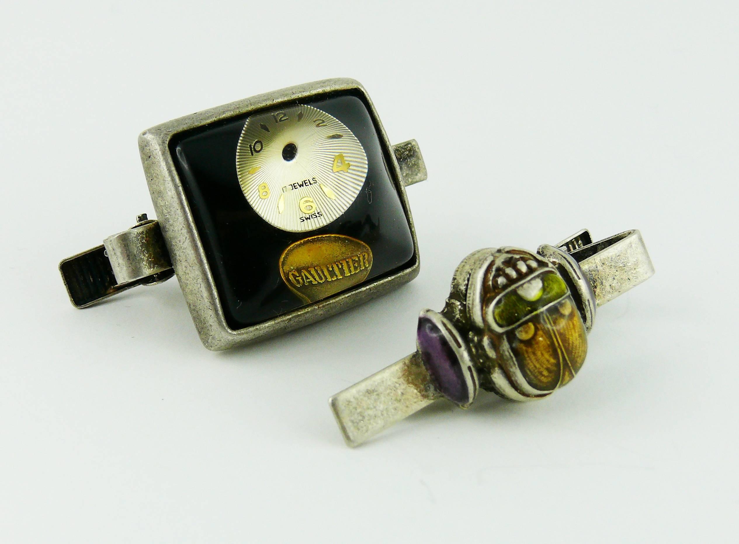 JEAN PAUL GAULTIER vintage 1990s lot of 2 rare tie clips.

One clip features a watch dial inlaid in a domed resin cabochon.
The other features an enameled scarab.

Silver tone setting with antique patina.

Marked GAULTIER on the watch dial clip.
The