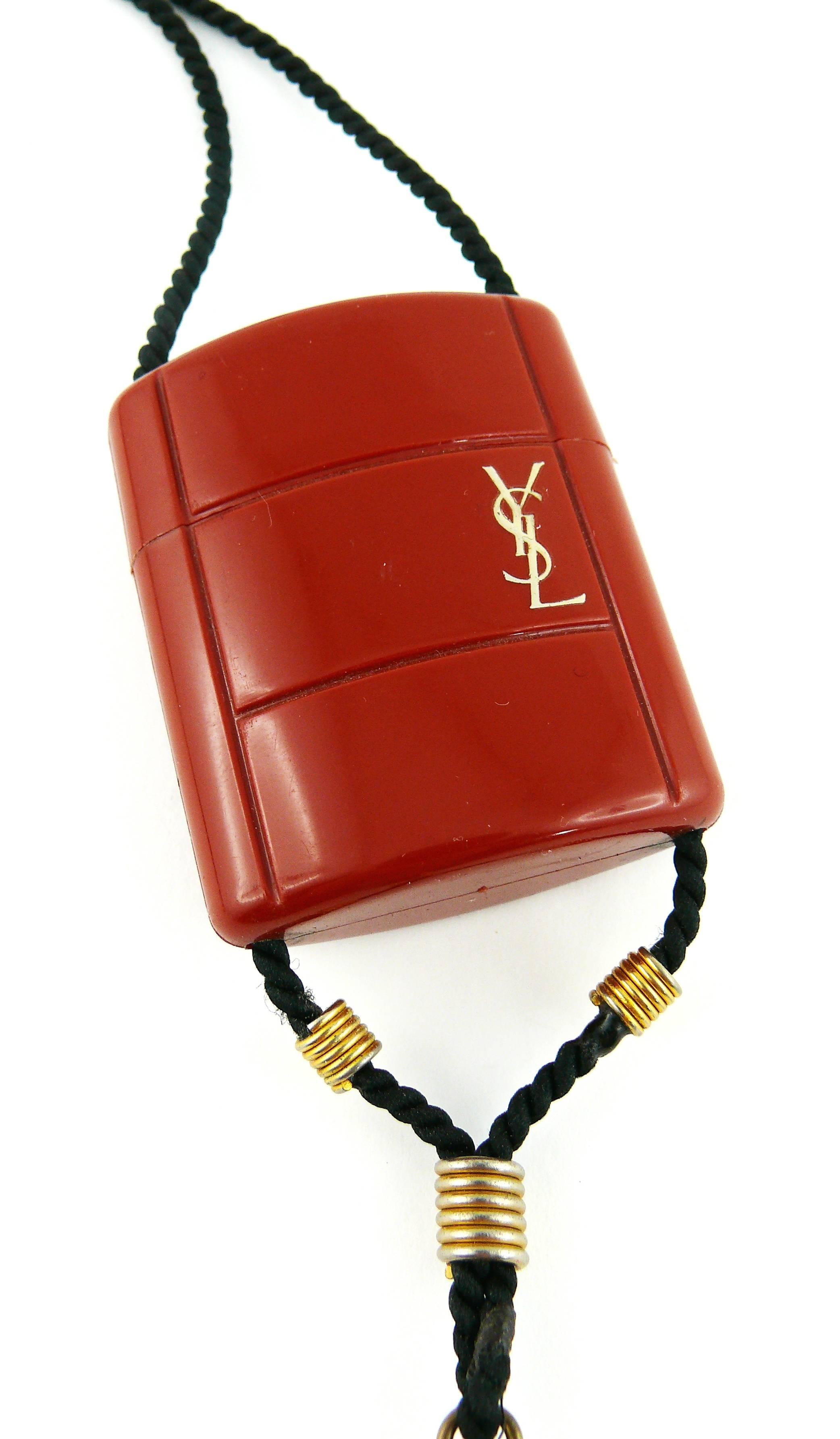 YVES SAINT LAURENT vintage Opium inro style pendant necklace.

This necklace consists of a black cord, a burnt orange plastic container, a silk tassel adorned with black and gold tone beads.

Plastic container opens to insert a miniature