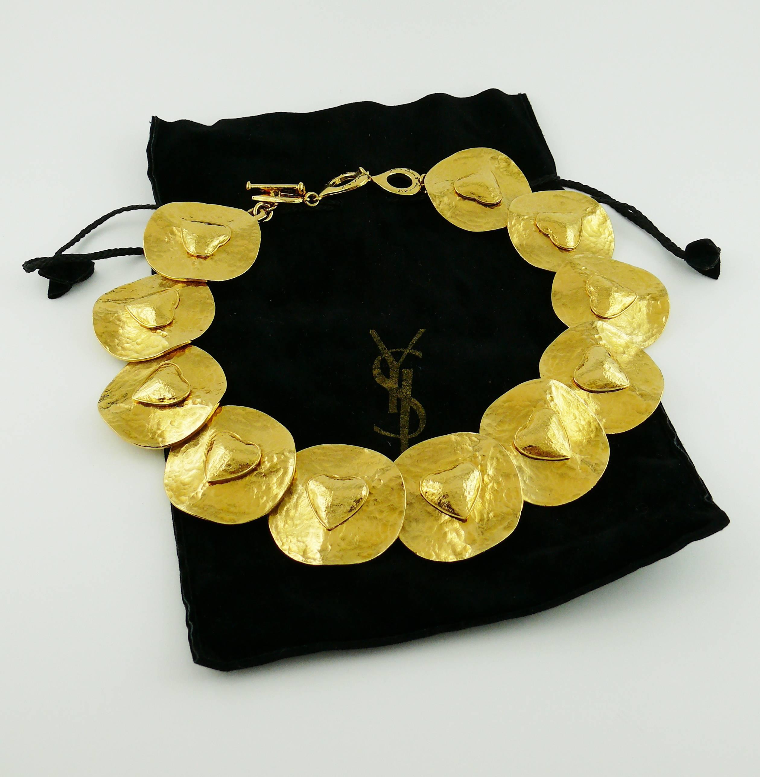 YVES SAINT LAURENT vintage rare gold toned choker necklace featuring textured creased discs with heart appliqués.

Signed YVES SAINT LAURENT Made in France on the iconic 