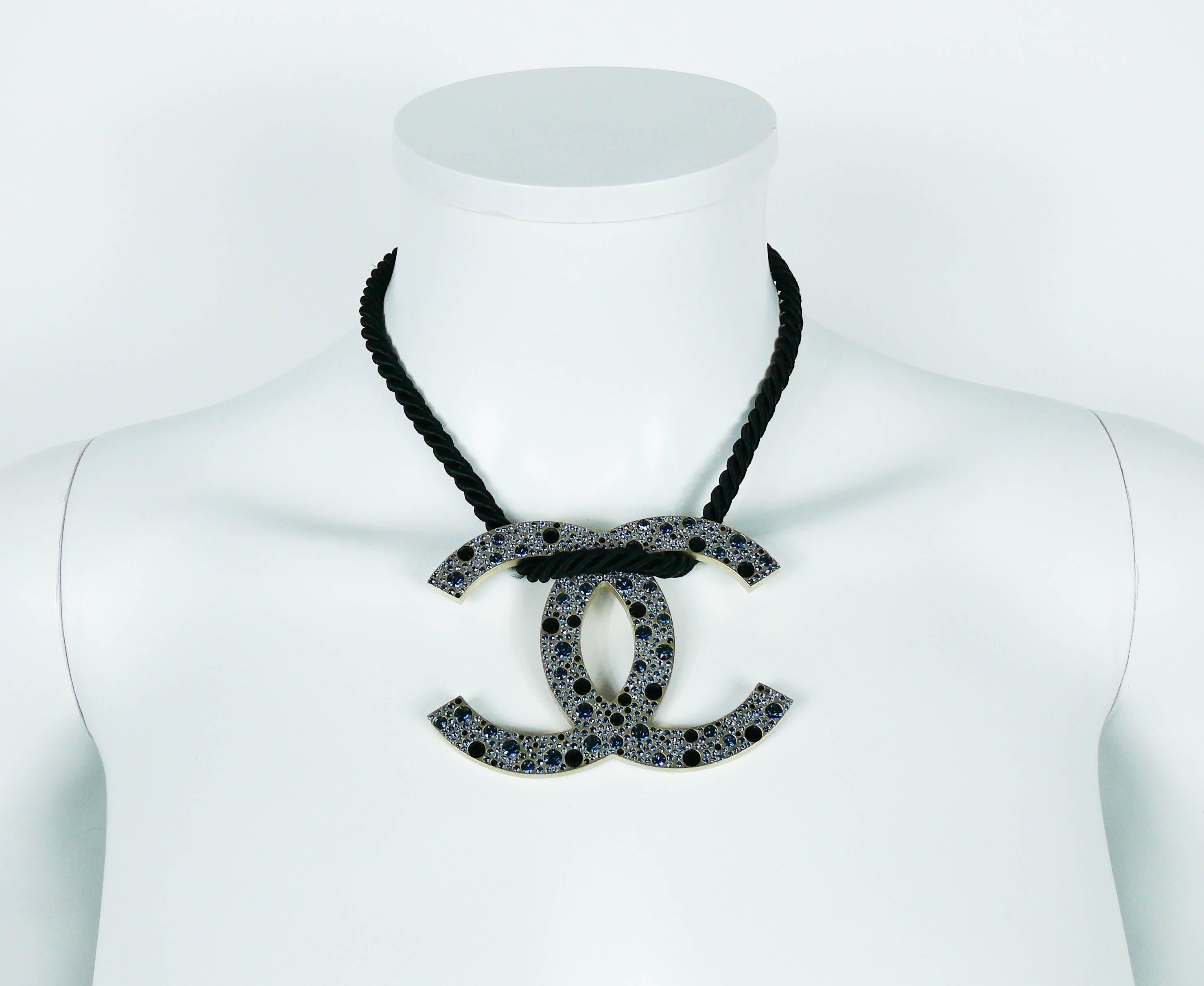 CHANEL rare jumbo CC logo pendant necklace embellished with blue shade SWAROVSKI crystals.

Spring-Summer 2008 Collection.

This necklace features :
- Brushed metal with pale gilt.
- SWAROVSKI crystals in blue shade.
- Black braided rope.
- Hook