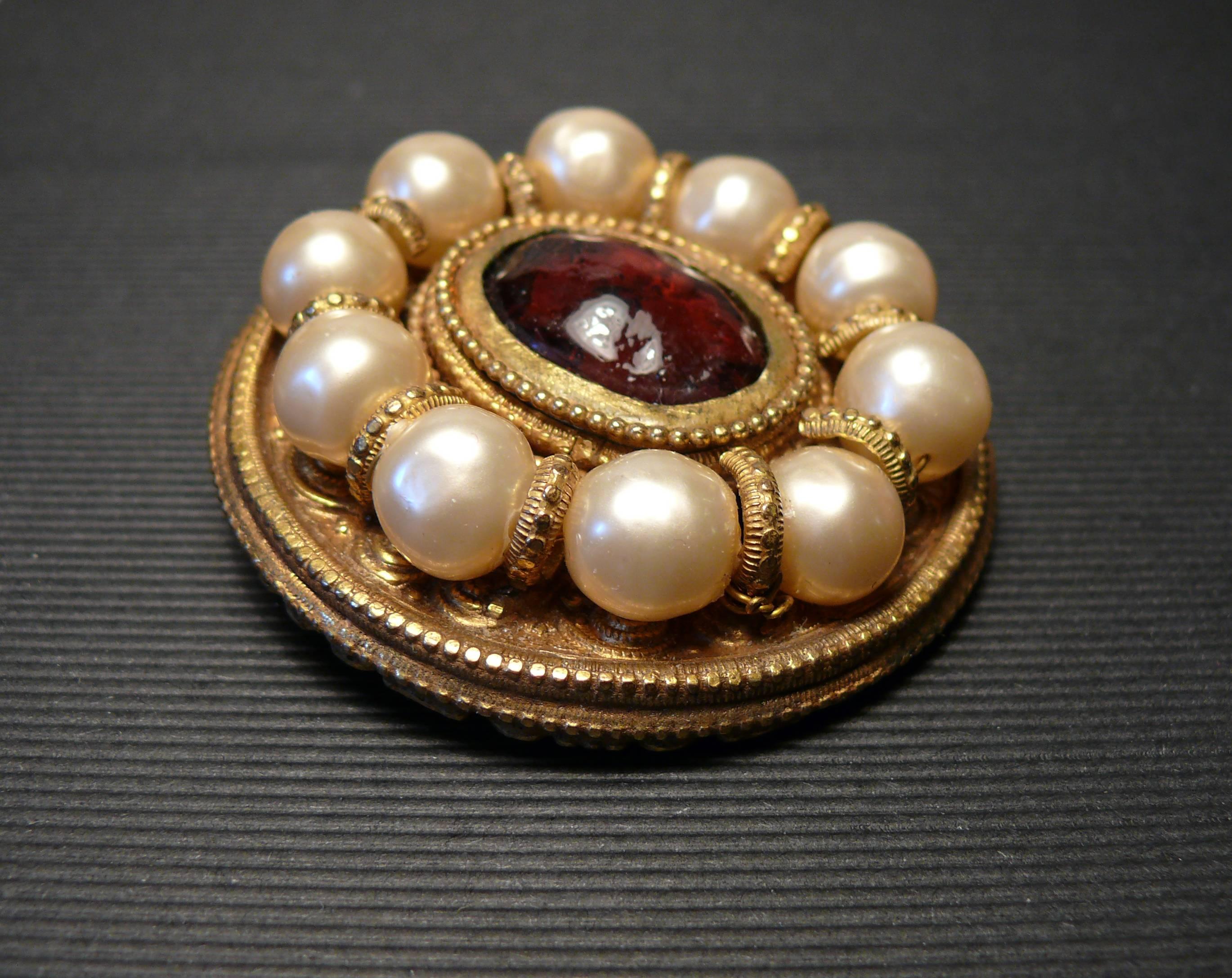 CHANEL vintage Baroque brooch featuring faux pearls and red-purple GRIPOIX pate de verre cabochon in a gold toned with antique patina setting.

Marked CHANEL Made in France.

Indicative measurements : diameter approx. 5 cm (1.97 inches).

JEWELRY