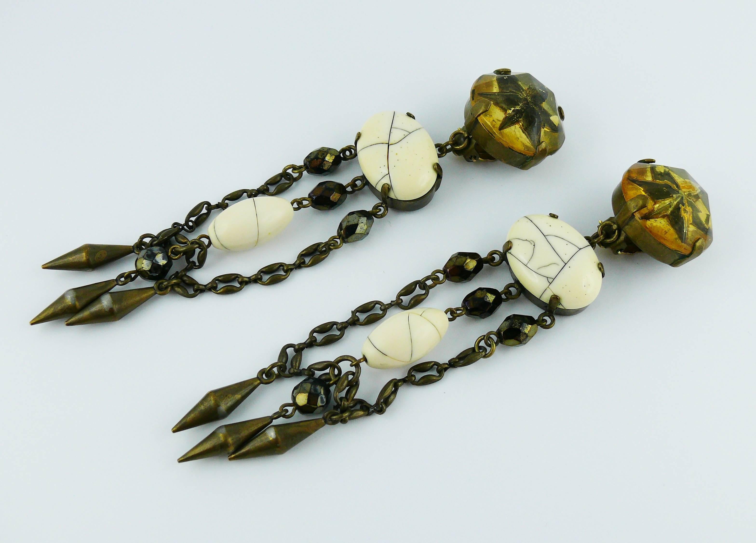 JEAN PAUL GAULTIER vintage antiqued bronze tone shoulder duster dangling earrings (clip-on) featuring star inlaid resin top, cracked faux stone cabochons, faceted glass beads and metal drops.

Marked JPG on the reverse.

Indicative measurements :