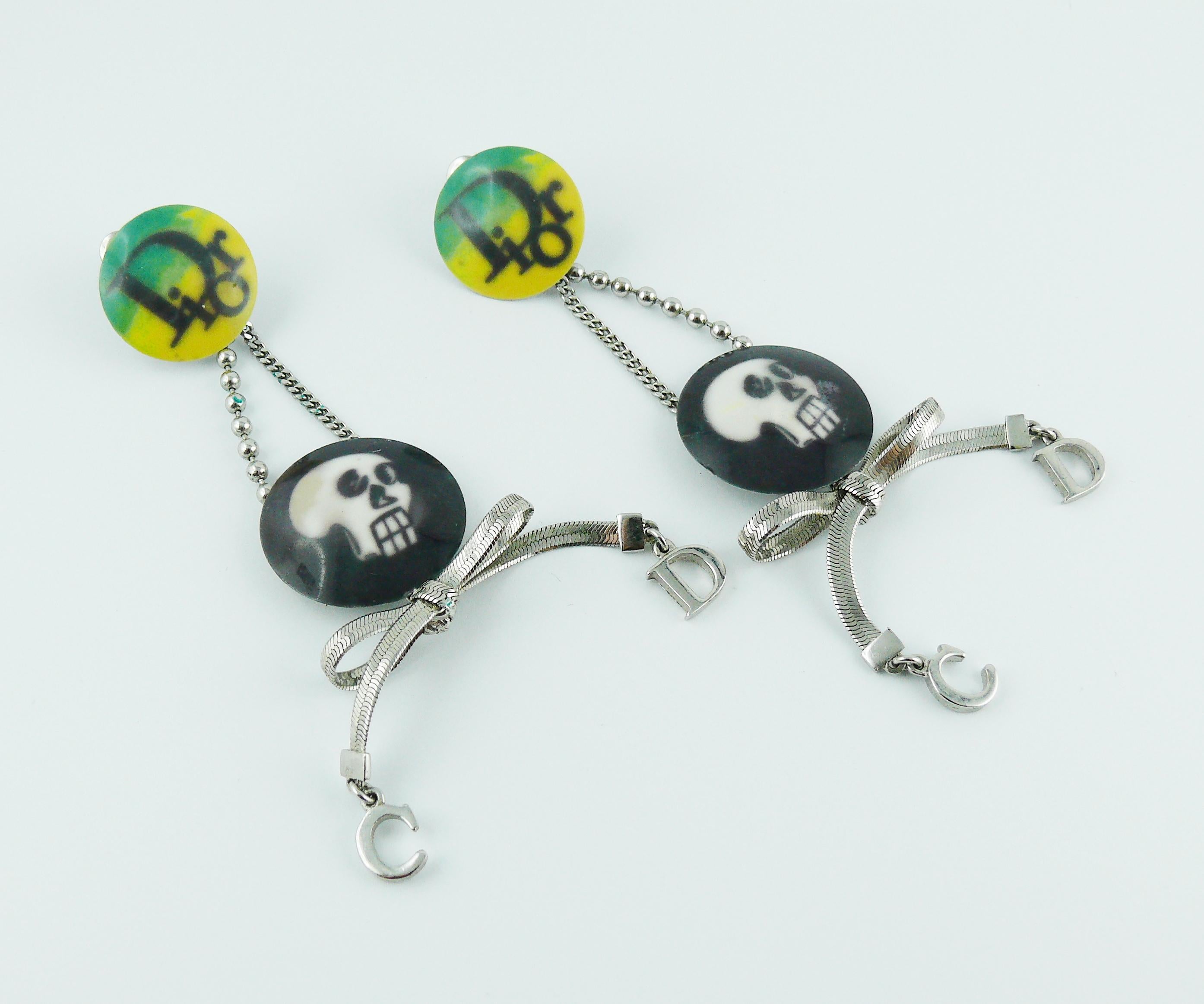 CHRSITIAN DIOR silver toned dangle earrings (clip-on) featuring a skull print coin and hanging CD initials.

Unmarked.

Indicative measurements : length approx. 10 cm (3.94 inches) / max. width approx. 3 cm (1.18 inches).

JEWELRY CONDITION CHART
-