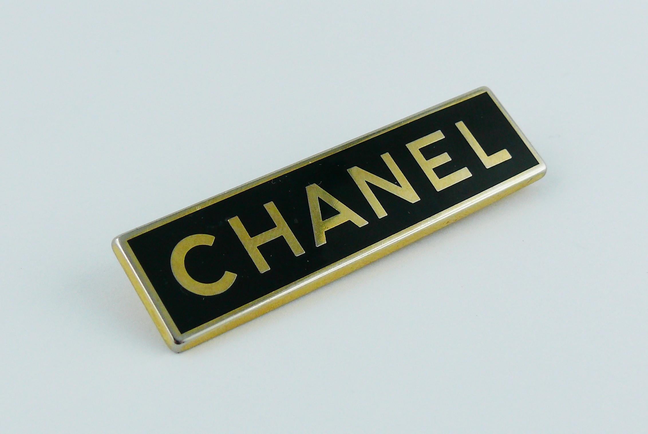 CHANEL vintage rectangular brooch featuring a black background with C-H-A-N-E-L letters in a gold toned setting.

This brooch was part of a CHANEL employee uniform.

Marked ARTHUS BERTRAND PARIS.

Indicative measurements : length approx. 5.2 cm