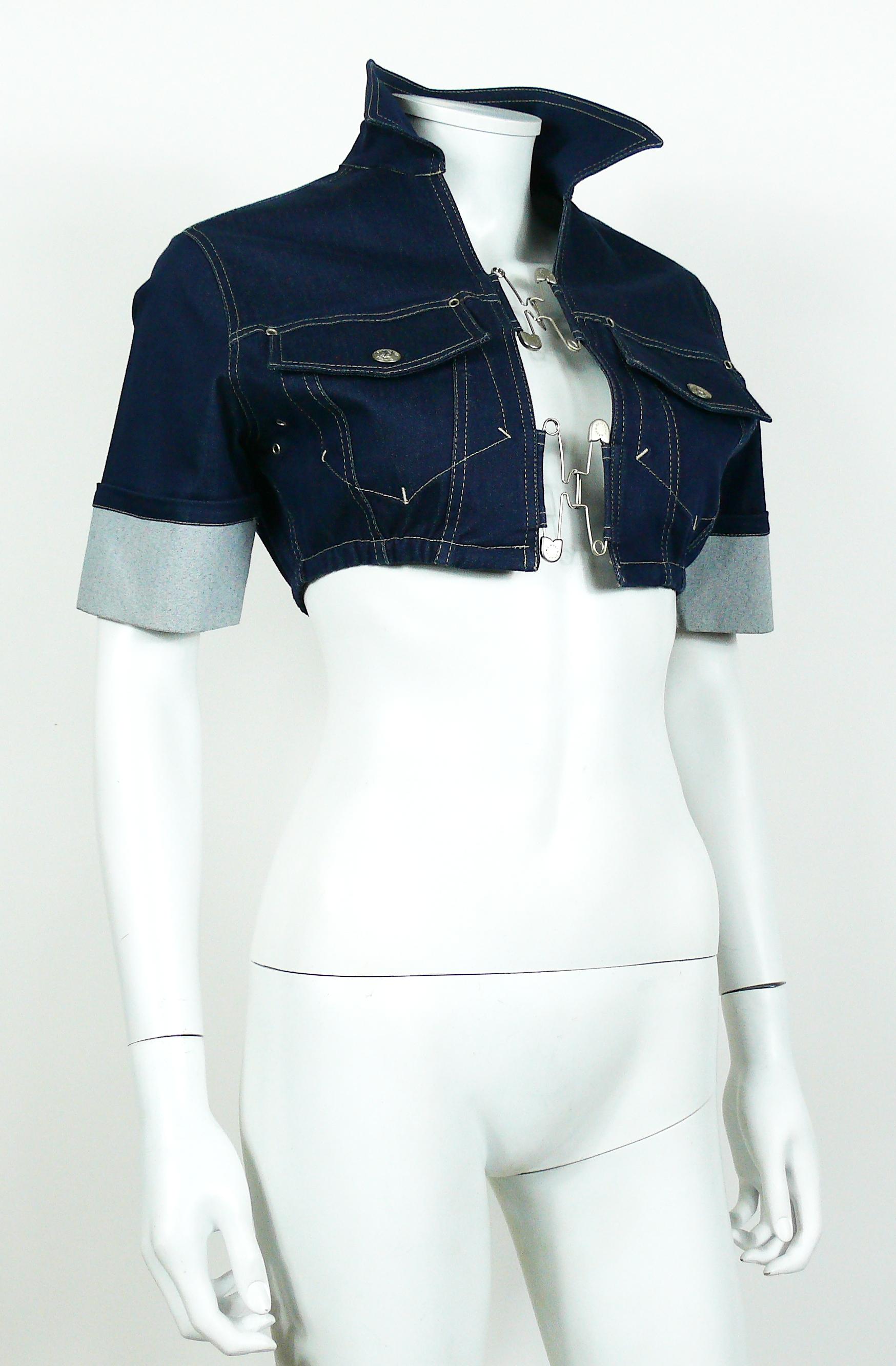 JEAN PAUL GAULTIER vintage denim crop top with interlocking safety pin closure at front.

This jacket features :
- Blue denim stretch fabric.
- Silver toned hardware.
- Large safety pins at front.
- Short sleeves.
- Classic collar.
- Two chest