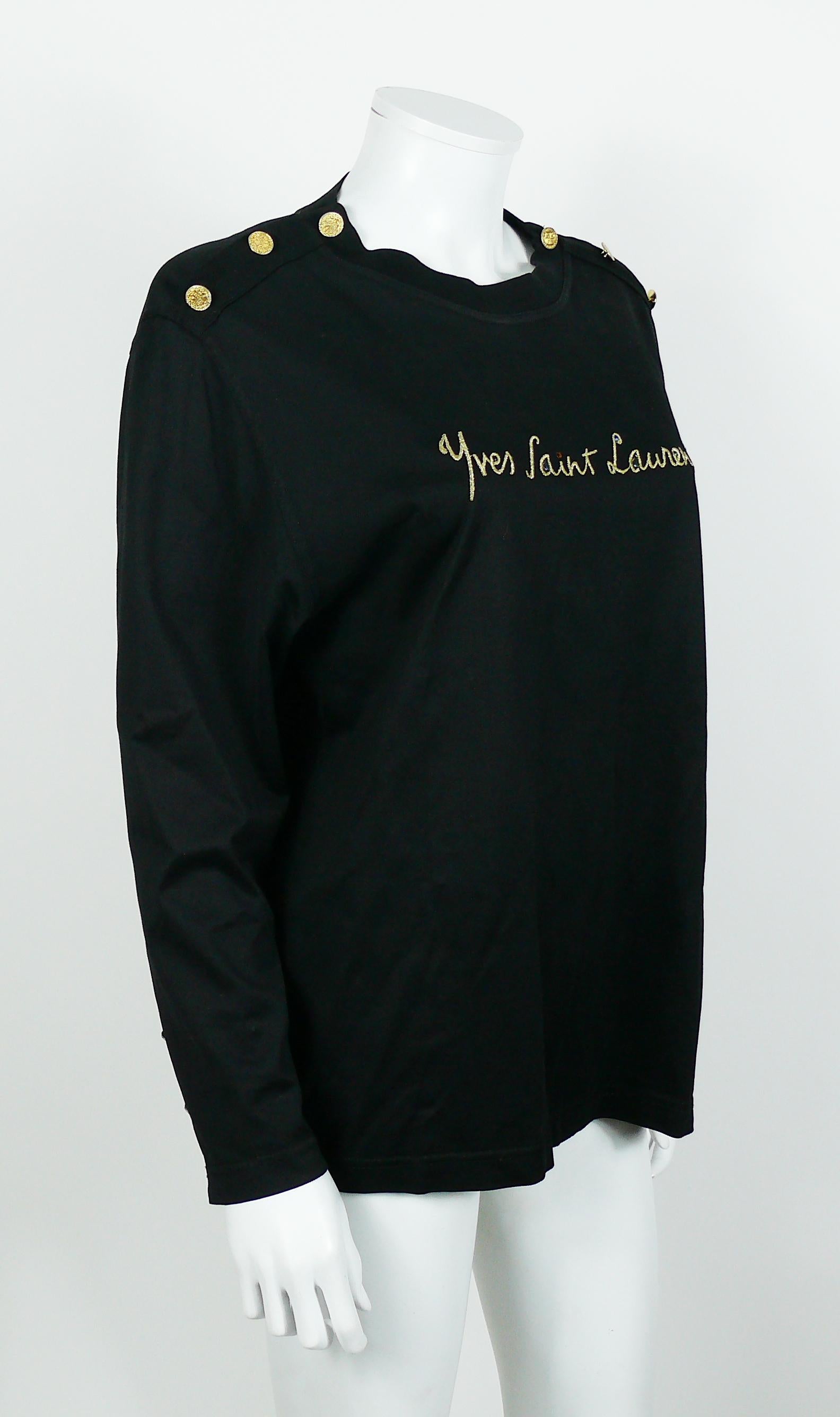 Yves Saint Laurent Variation vintage black top featuring a gold embroidered cursive signature embellished with multicolored resin crystals.

Coat of arms gold toned buttons on shoulders and cuffs.

Label reads YVES SAINT LAURENT VARIATION.

Size