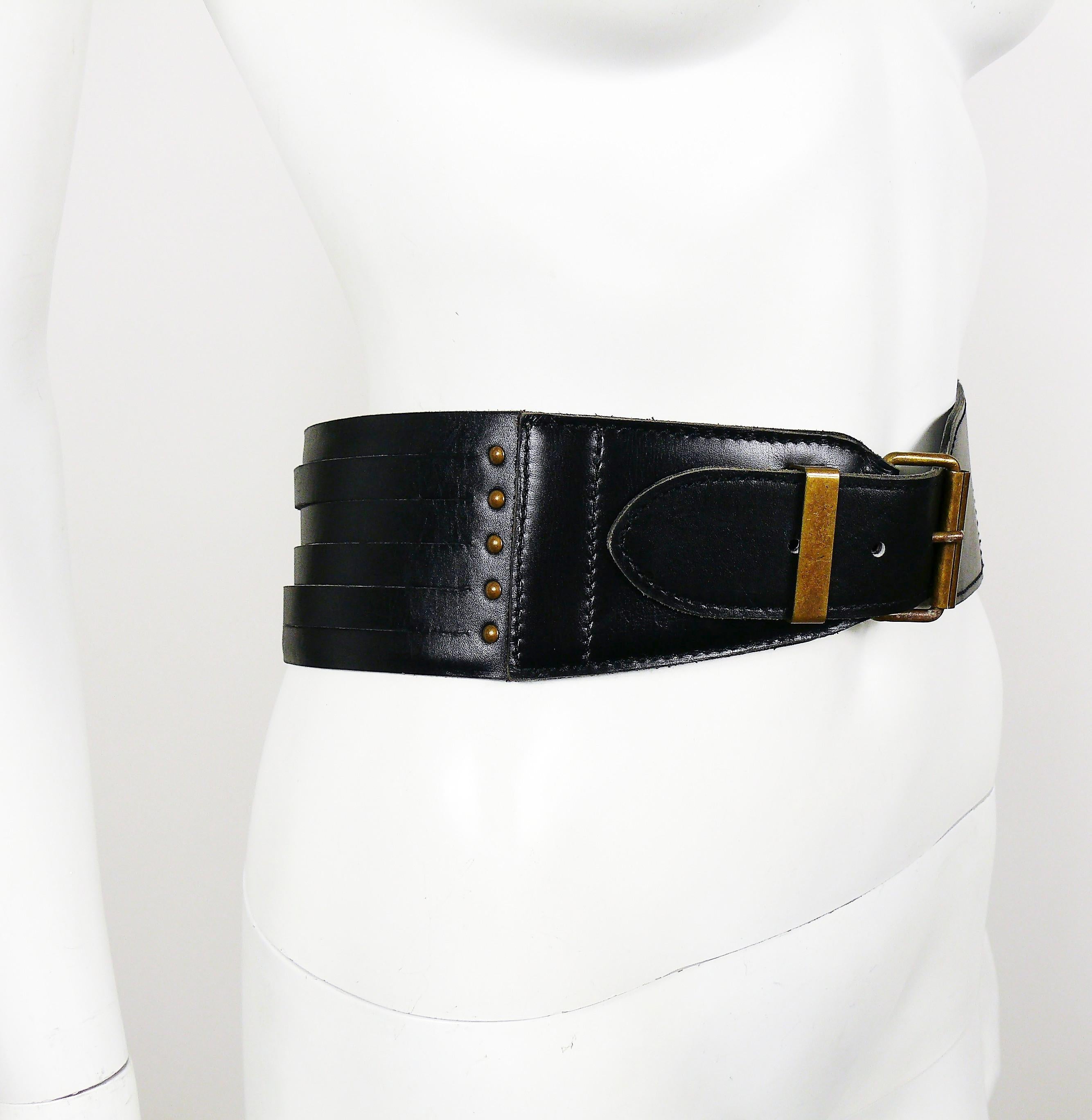 ALAIA Vintage schwarzer Ledergürtel mit hoher Taille, der auf der Rückseite ein Korsett mit mehreren Streifen zum Schnüren und Nieten an den Seiten aufweist.

Bronzefarbene Hardware.

Gekennzeichnet mit ALAIA PARIS.
Hergestellt in