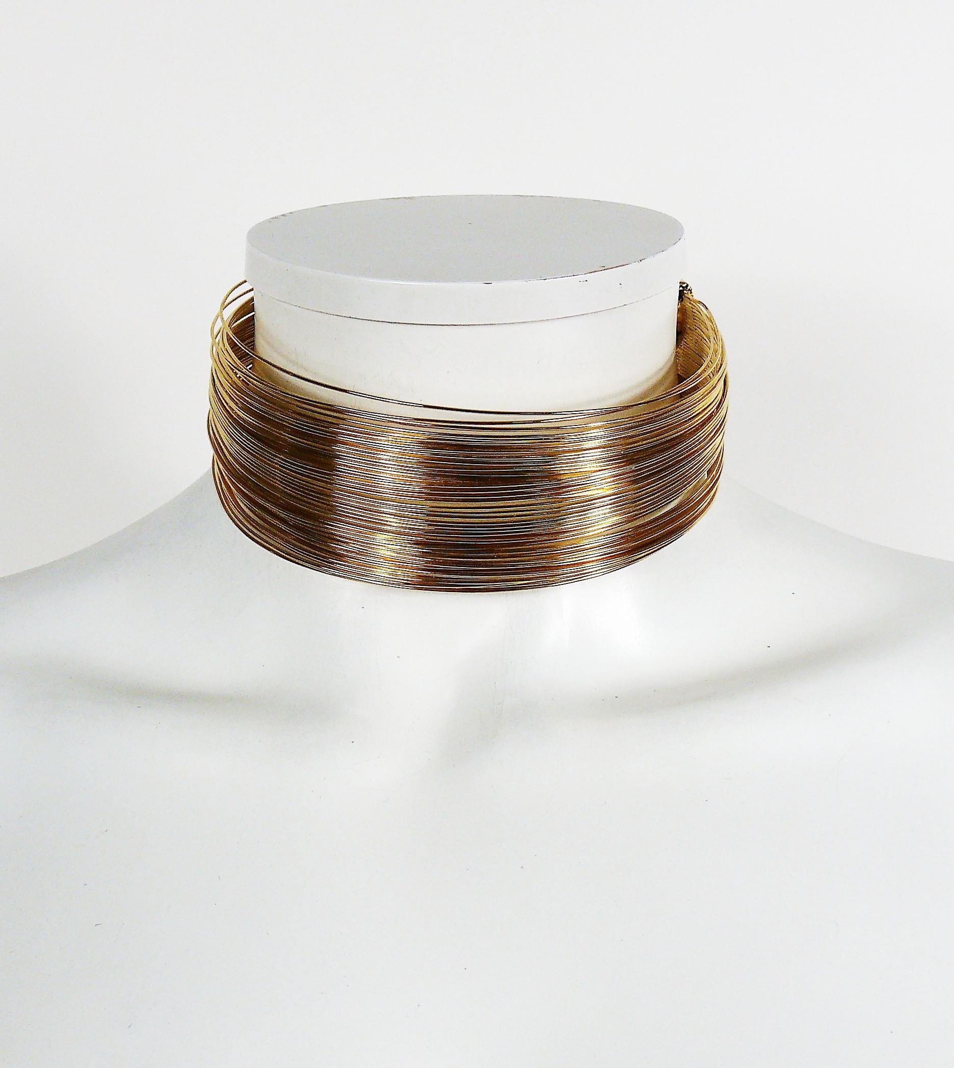 Collier ras de cou J'ADORE iconique de Christian Dior en fil d'or.

Créé par le parurier français HERVE VAN DER STRAETEN pour Dior.

J'ADORE en relief sur les poignées et PARFUMS CHRISTIAN DIOR à l'intérieur.

Mesures indicatives : circonférence