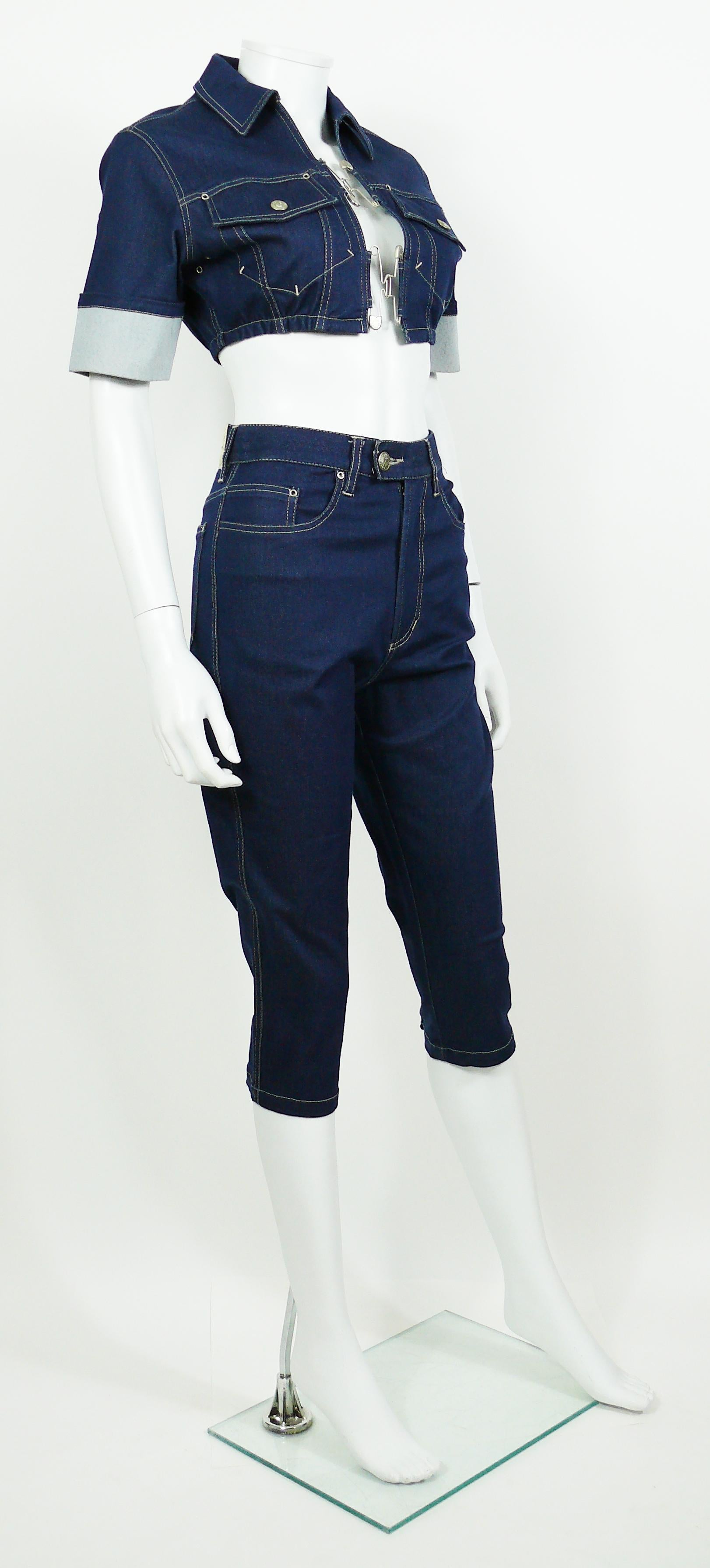 JEAN PAUL GAULTIER vintage denim ensemble featuring a crop top and a cropped trousers.

JACKET features :
- Blue denim stretch fabric.
- Silver toned hardware.
- Large safety pins at front.
- Short sleeves.
- Classic collar.
- Two chest pockets with