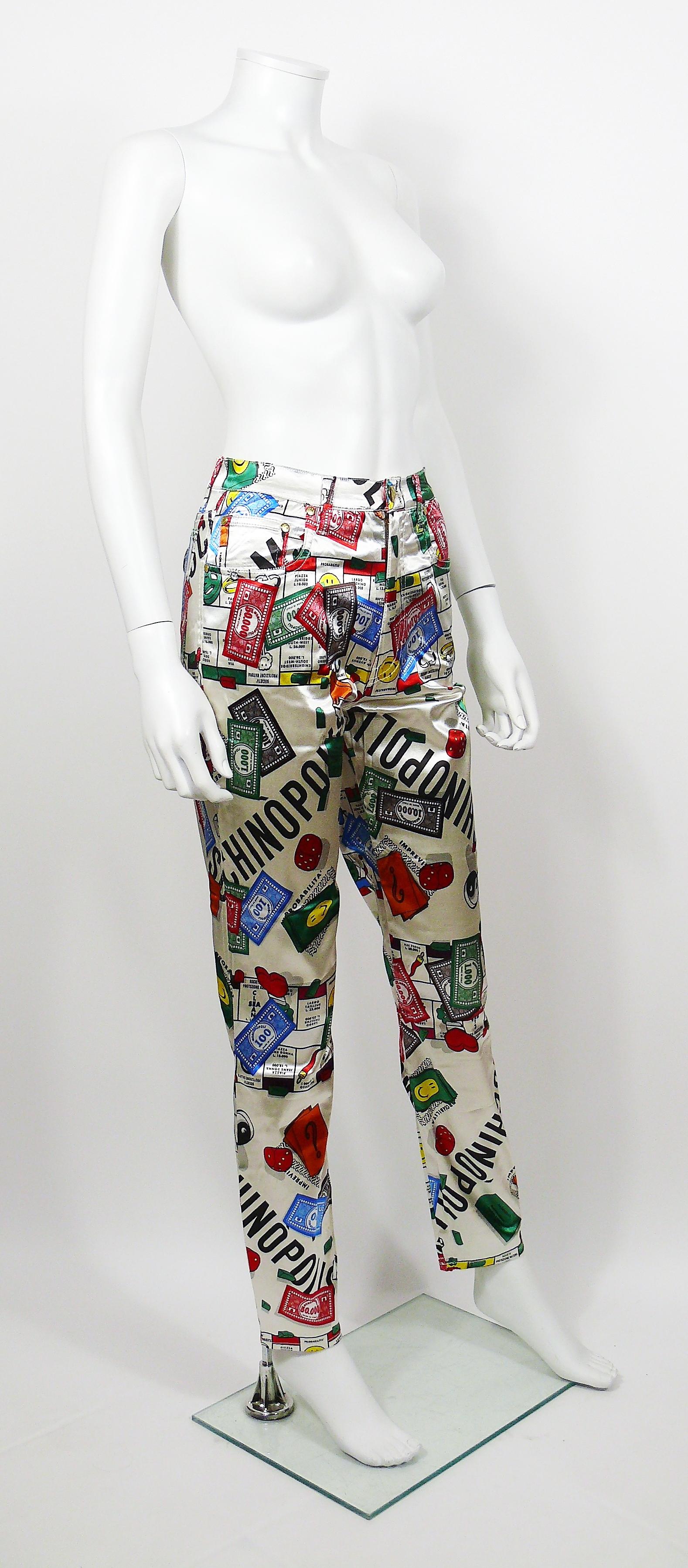 Pantalon vintage iconique des années 1990 MOSCHINO présentant un opulent imprimé du jeu Monopoly Moschinopolis multicolore sur fond blanc.

Ce pantalon est doté de :
- Matière brillante et extensible.
- Boutonnage et fermeture éclair sur le