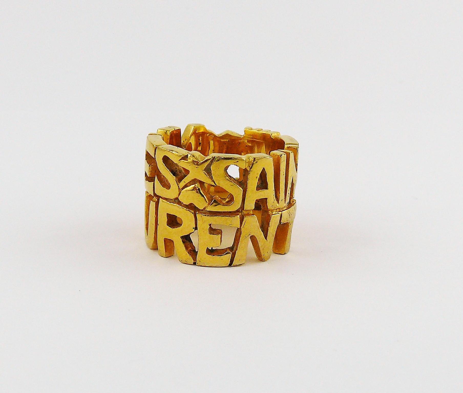 YVES SAINT LAURENT vintage gold toned ring featuring YVES SAINT LAURENT lettering with hearts and stars.

Embossed YSL.

Indicative measurements : inner circumference approx. 5.65 cm (2.22 inches) / width approx. 1.6 cm (0.63 inch).

JEWELRY